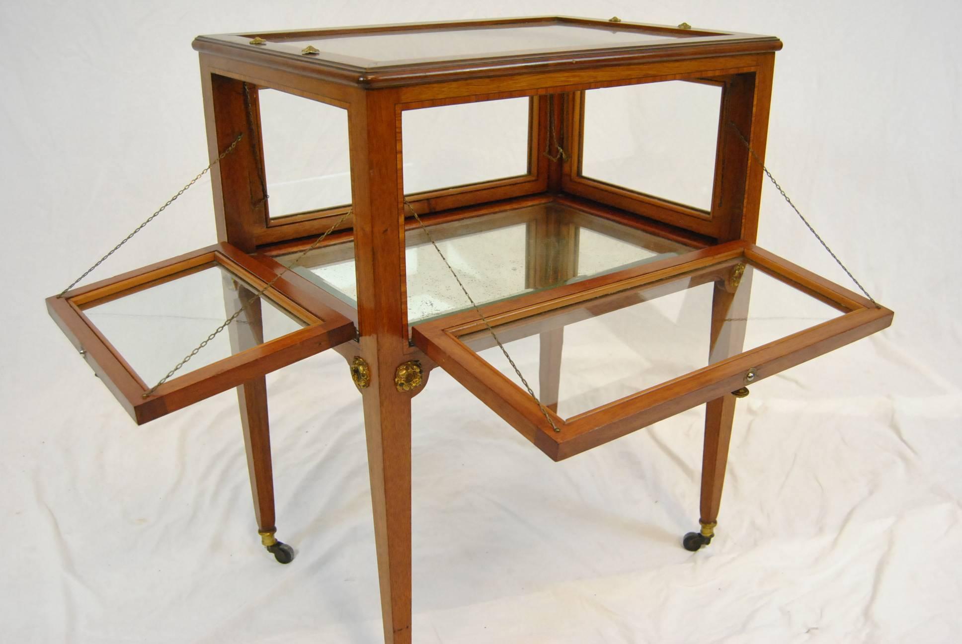 A beautiful mahogany and burled walnut etagere butler server, tea cart. This lovely piece features a glass case with pull down sides for easy access, brass piano hinges, ornate brass handles and a satinwood inlaid border.