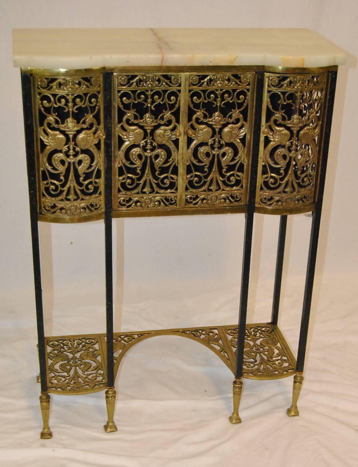 A unique bronze and iron telephone stand in the style of Oscar Bach. Stand has an onyx top with a heavy vein down the center. The back has a slot with slip in a door to allow for the telephone cord. The four doors on the front have ornate pierced