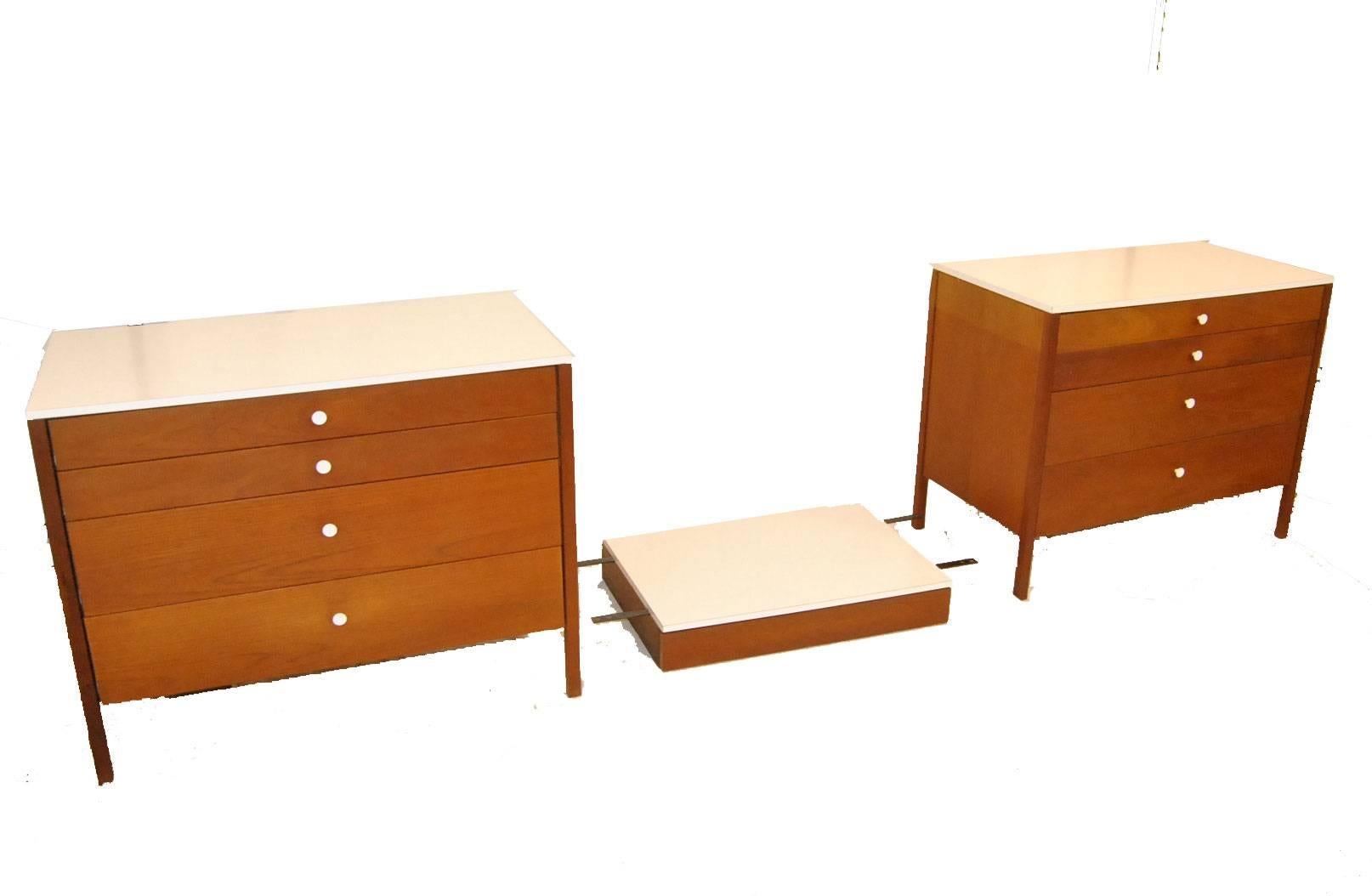A great three-piece dresser set in very good original condition by Florence Knoll. The set includes two four-drawer chests with white metal pulls and a floating desk / vanity with one drawer. Tops and backs are done in white laminate. Original tag
