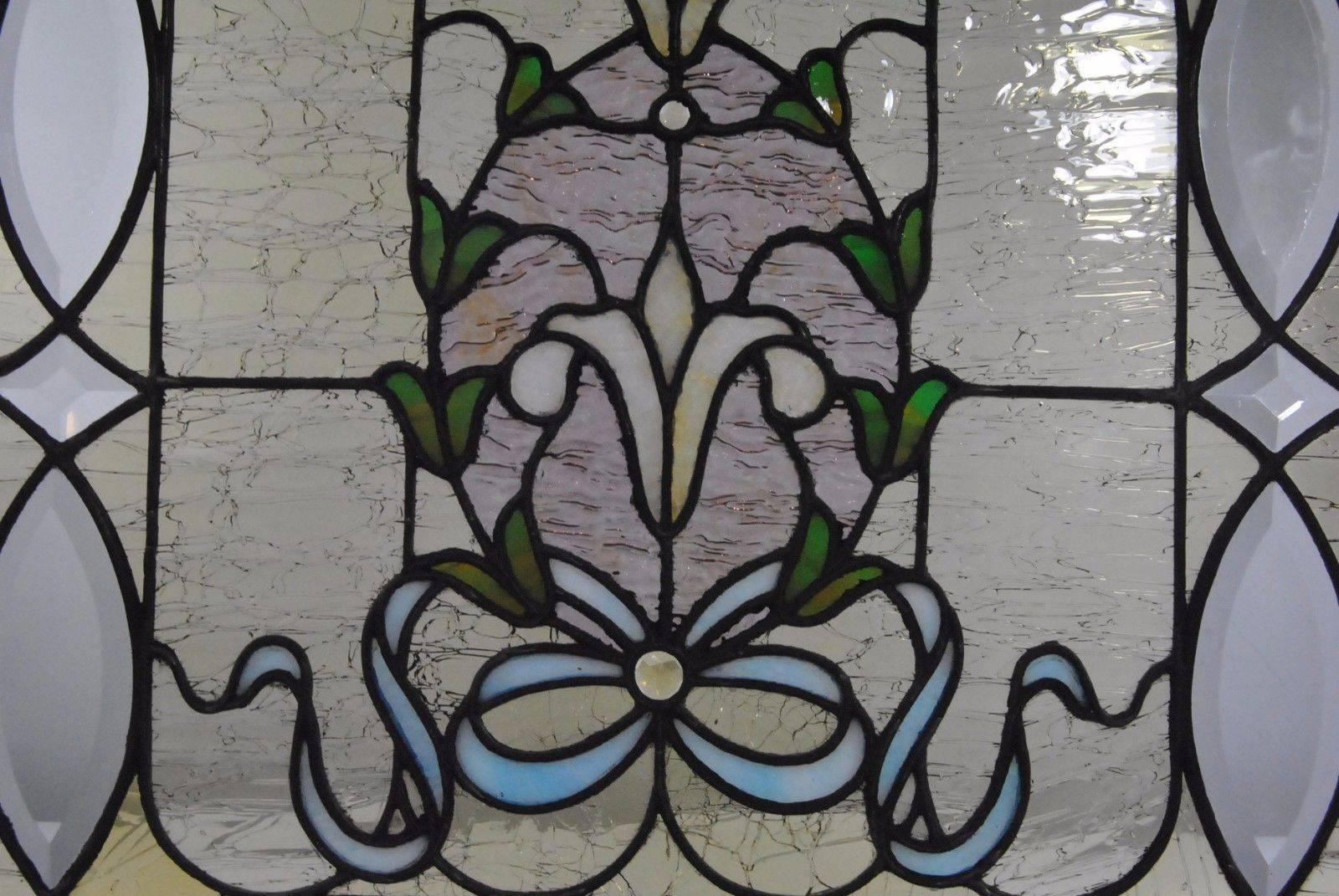 Antique stained glass and beveled cut window. Fine leadwork. Center design features a flowing blue ribbon and bow with jewel accents. Suspended tulips surrounded by bell flowers. Border has beveled cut-glass details. Measures: There are two small