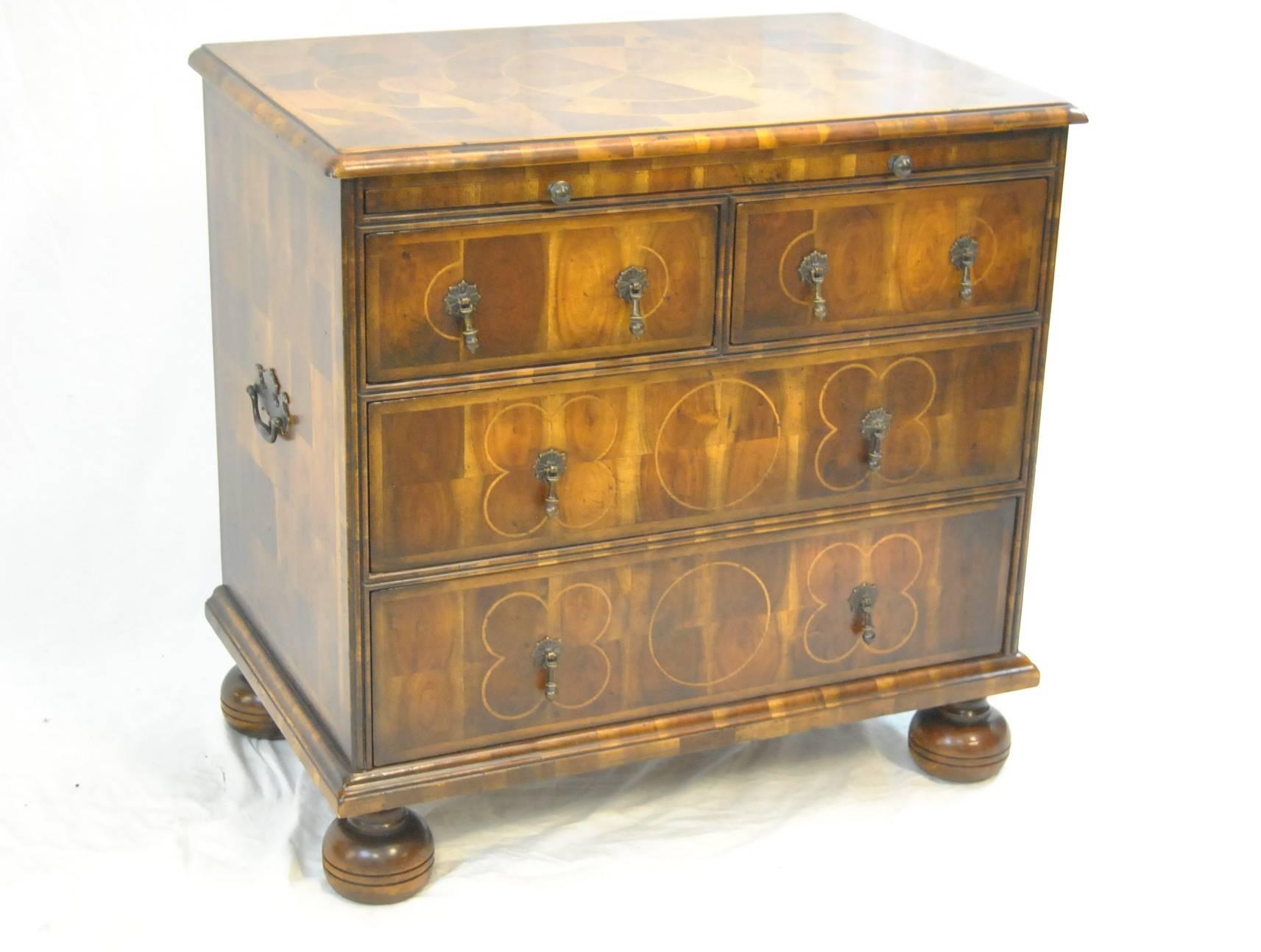 A stunning oyster walnut bachelor chest by Theodore Alexander. It features four dovetailed drawers, bunn feet, a pull-out shelf with a leather insert and a fleur de lis pattern. It also has a parquetry inlaid top and sides with cross grain moulding.
