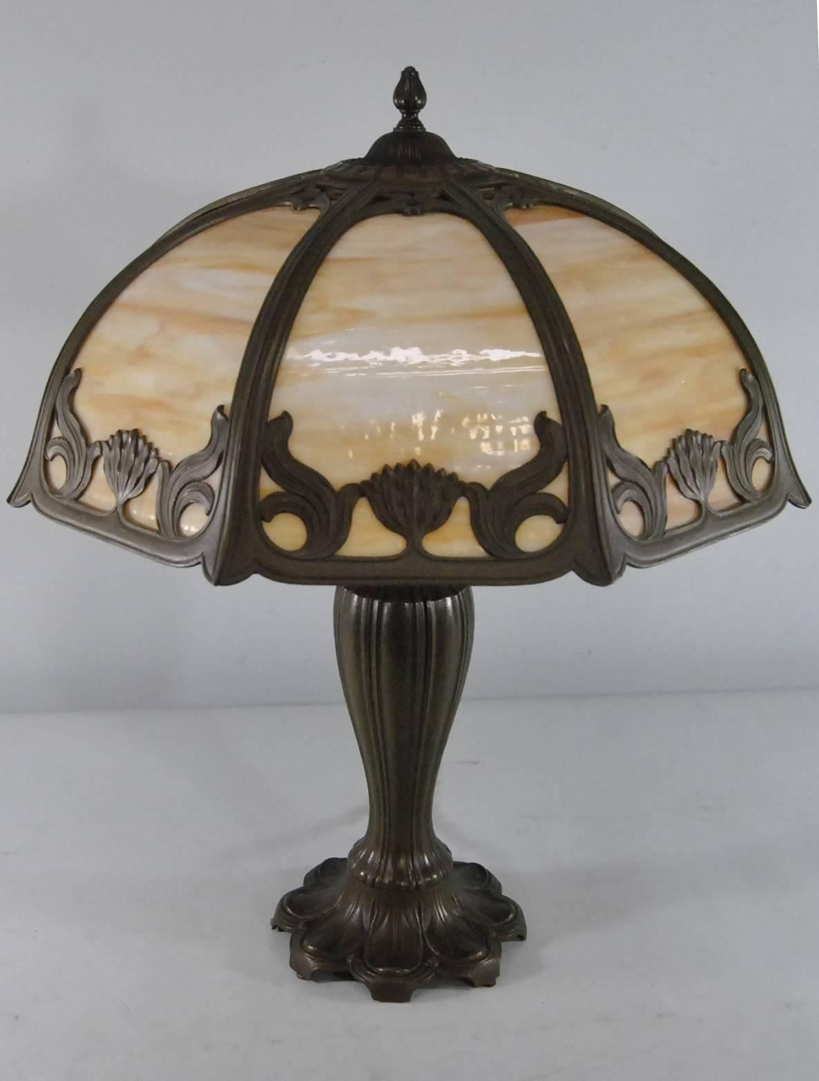 A beautiful Art Nouveau slag glass lamp by Miller. The lamp has a metal base with an organic floral theme which carries over to the eight-panel lamp shade. There are two sockets which are original with chain pulls. The wiring is tested and lamp is