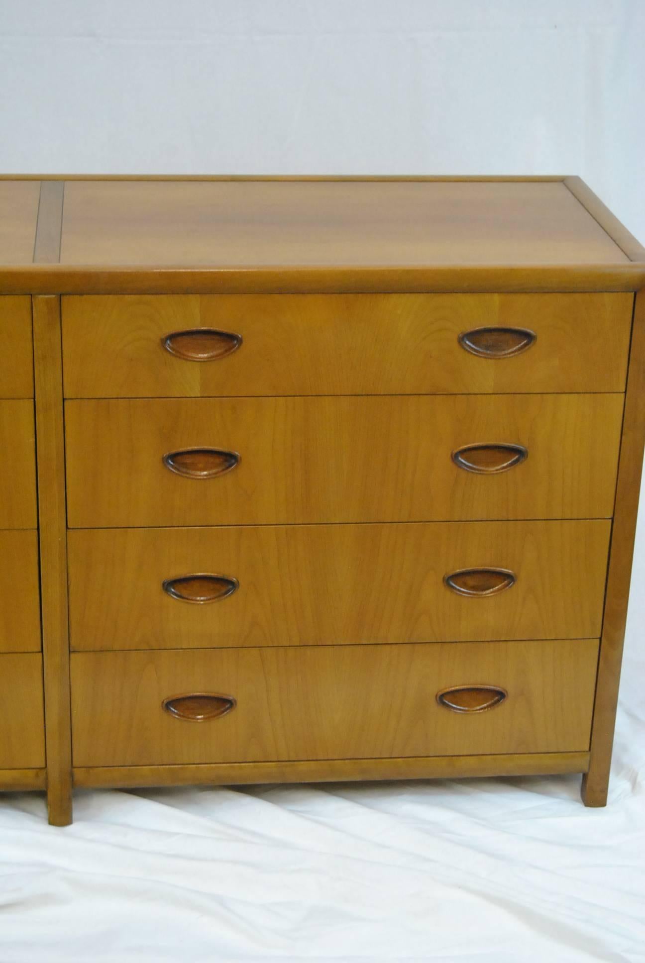 Clean classic lines define this eight drawer 62" chest by Baker furniture. This is part of the new World collection from the late 1950s. The chest has bookmatched cherry drawer fronts and top. Pulls are inset ovals on dovetailed drawers. It is