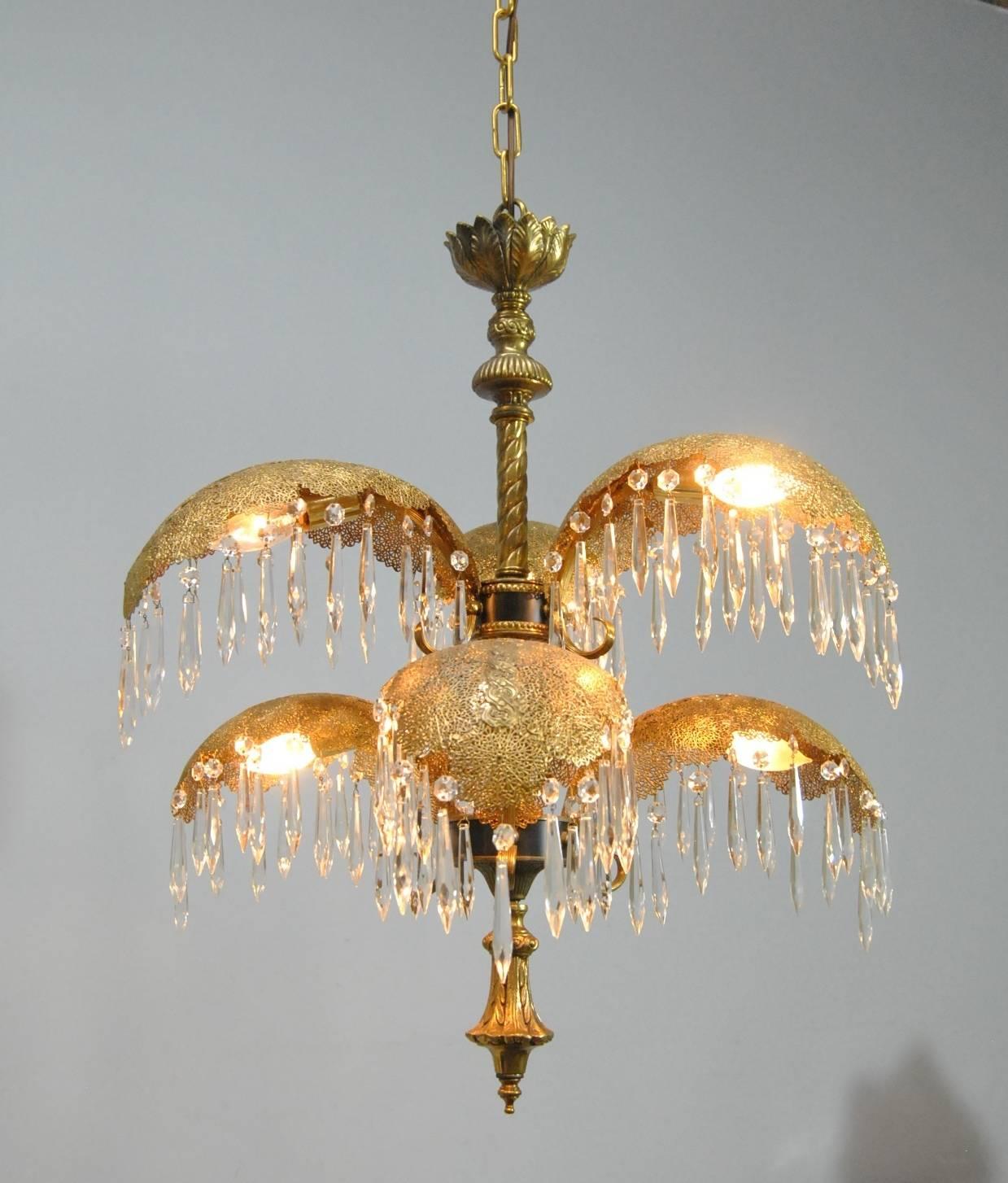 An unusual Italian brass chandelier. Chandelier has six palm frond style arms with hanging crystal prisms. Fronds are attached to a twisted brass rod with crown and lower finial carrying through the folage theme. The 28