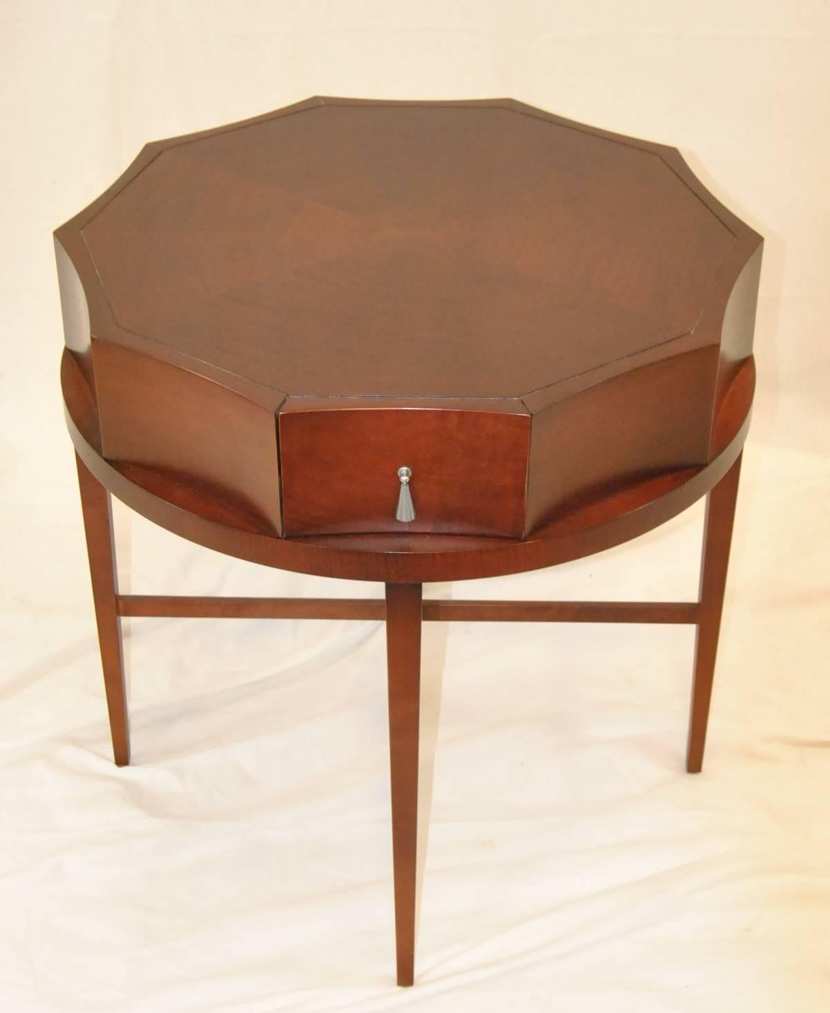 A great 26" in diameter mahogany side table by Baker Furniture. This is a table that can add style to any decor. The top features a scalloped edge and one dovetailed drawer with a pewter pull. The top sits on four tapered legs with cross