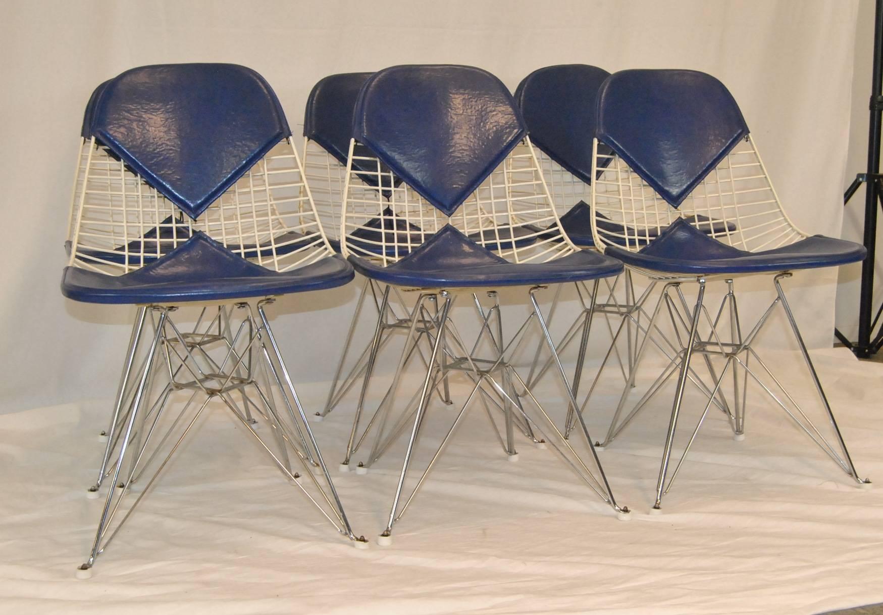 A great set of six (6) wire chairs designed by Charles Eames and produced by Herman Miller. The frame of the seats are powder coated wire with chrome legs. Chairs retain their original dark blue 'bikini' seat cover with Herman Miller tag. Overall