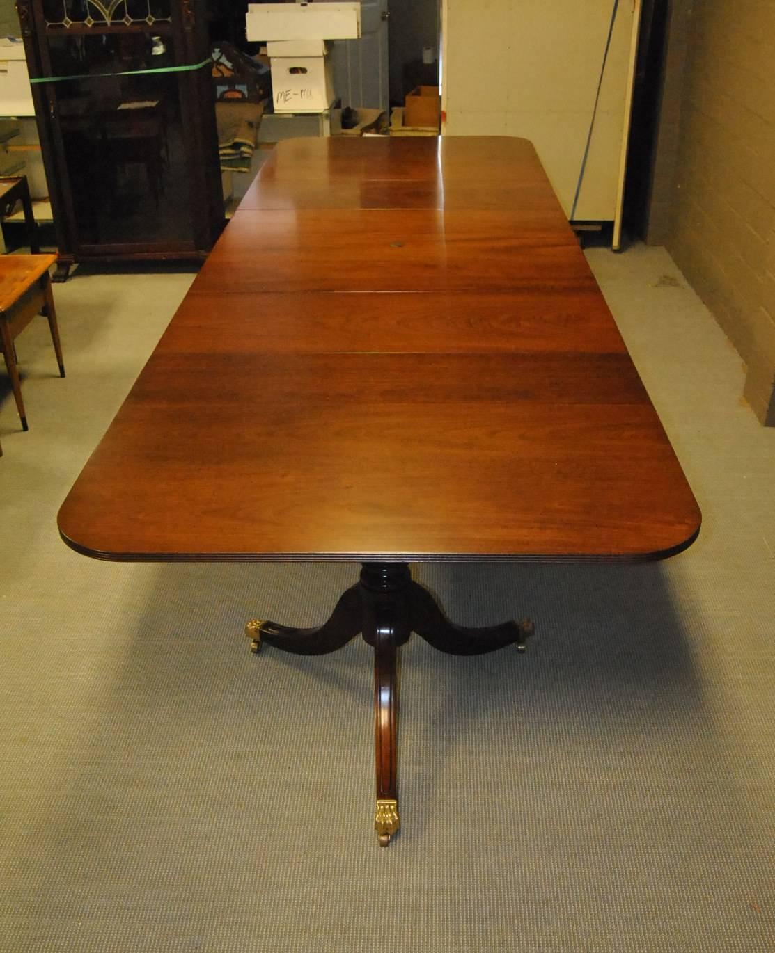 An unusual 18th century style mahogany conference table by Kittinger. The table features three pedestals (two with three legs and central pedestal with four legs). Each leg on the pedestal ends in a brass paw cap with caster. Measures: Without the