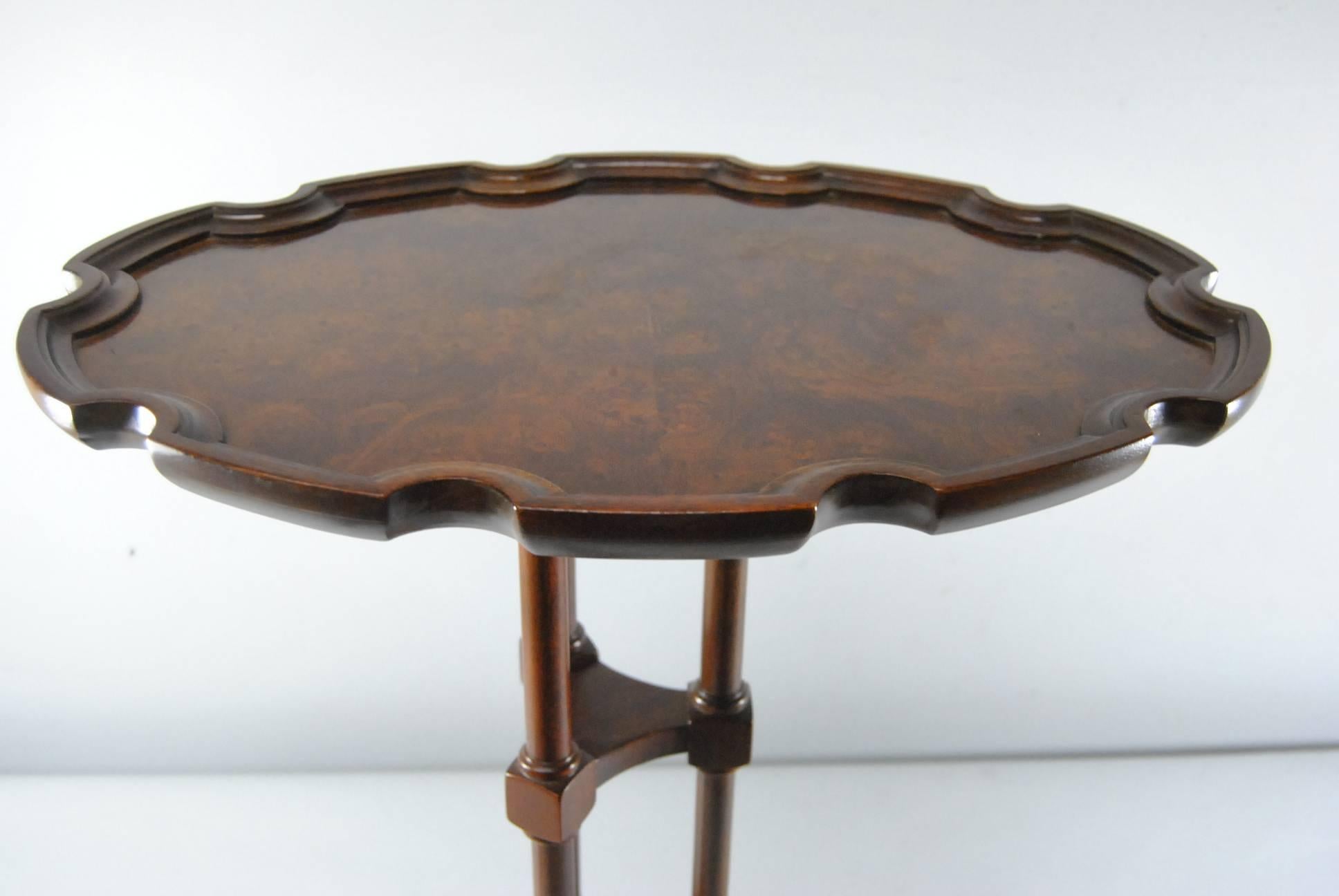 A great small-scale accent table by Baker Furniture as part of their Historic Charleston collection. The table features a stunning burl wood top with pie crust edge. Top is supported by three legs attached to triangular base with three paw feet.