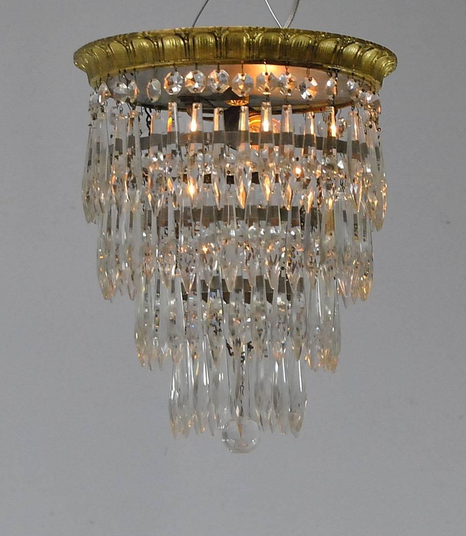 A great crystal wedding cake style chandelier. This small-scale chandelier is 12" tall and only 9.5" in diameter at the top and tapers to the bottom. It features four-tiers of hanging prisms which are lit by one socket. The flush mount