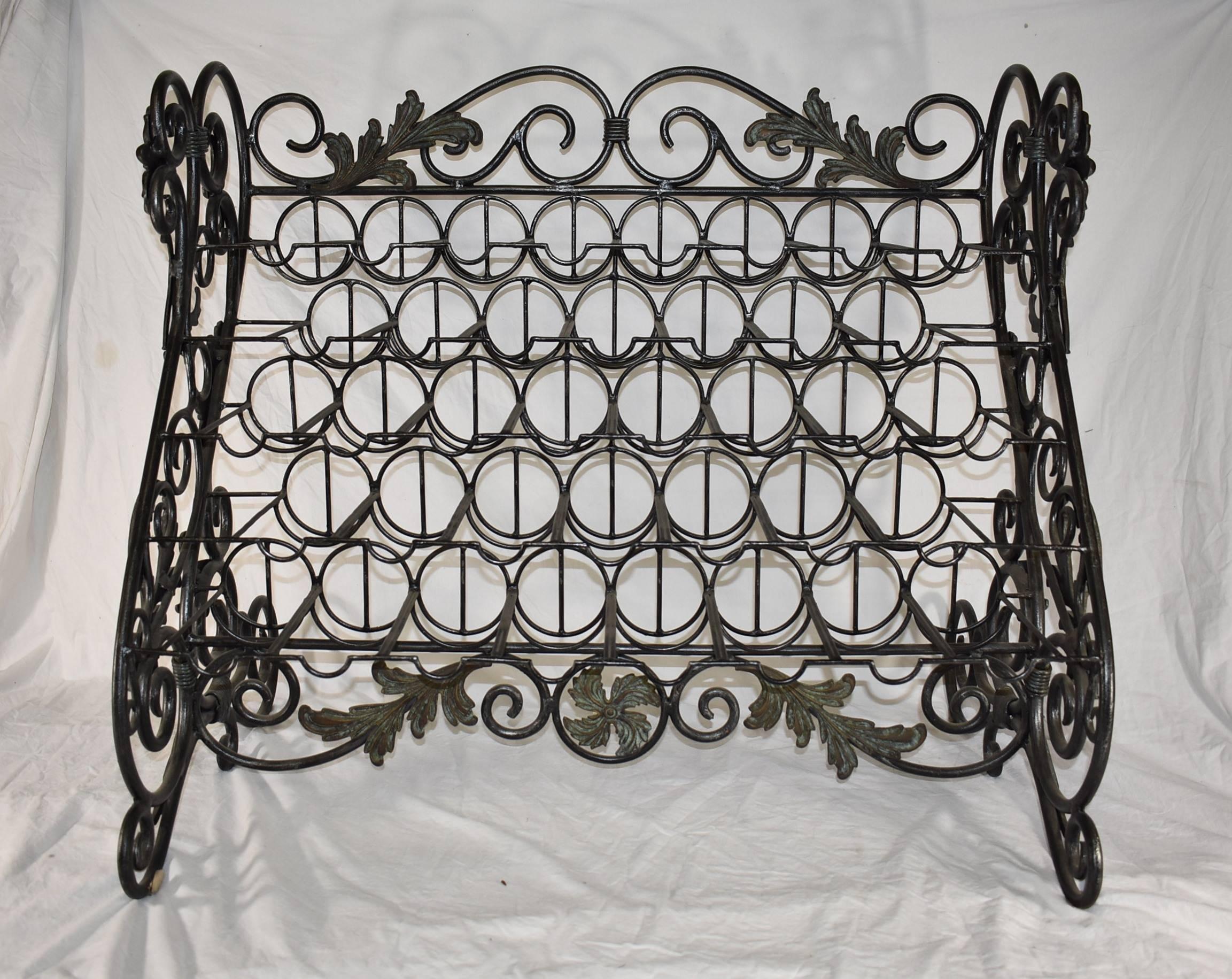 An unusual 38 bottle iron wine rack by Maitland-Smith. The sides are done in scroll work with leafs accents. A verdigris patina has been applied as accent. Original Maitland-Smith stick is on the back of the central medallion at bottom. Dimensions