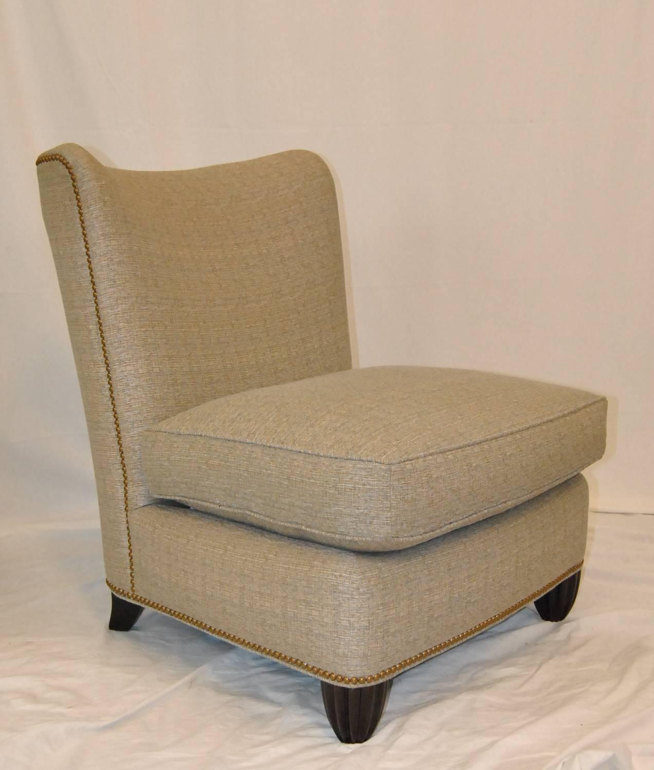 A great pair of armless lounge chairs designed by Barbara Barry for Baker Furniture. Chairs are upholstered in a neutral multi-color fabric which is accented with nailhead trim at base and around the sides and back. Bottom cushions are removable.