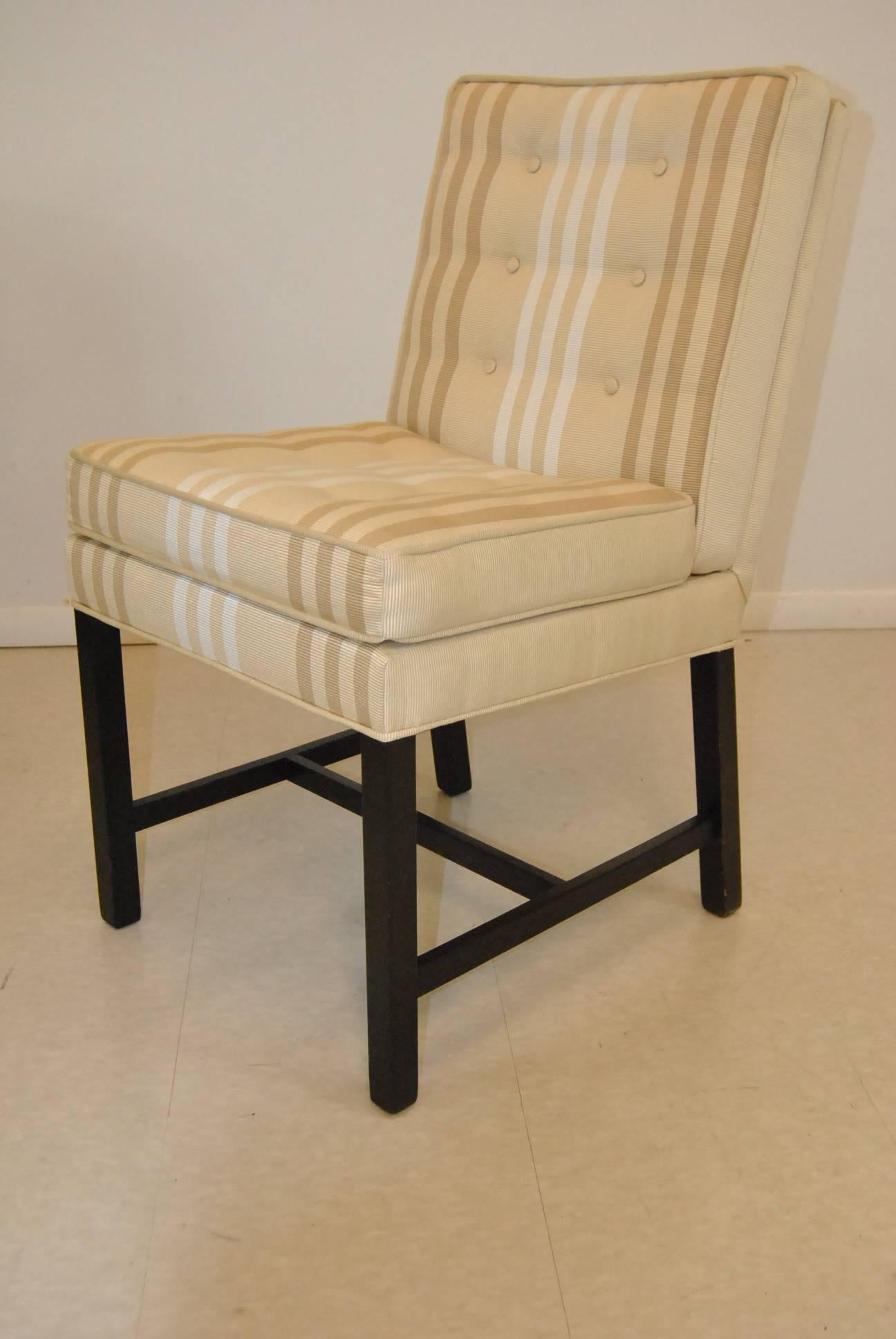 A great set of four upholstered dining side chairs by Dunbar. The chairs have hardwood frames with original ebonized finish. Chairs have tufted seats and back and are upholstered in a neutral cream cloth with white and tan stripes.