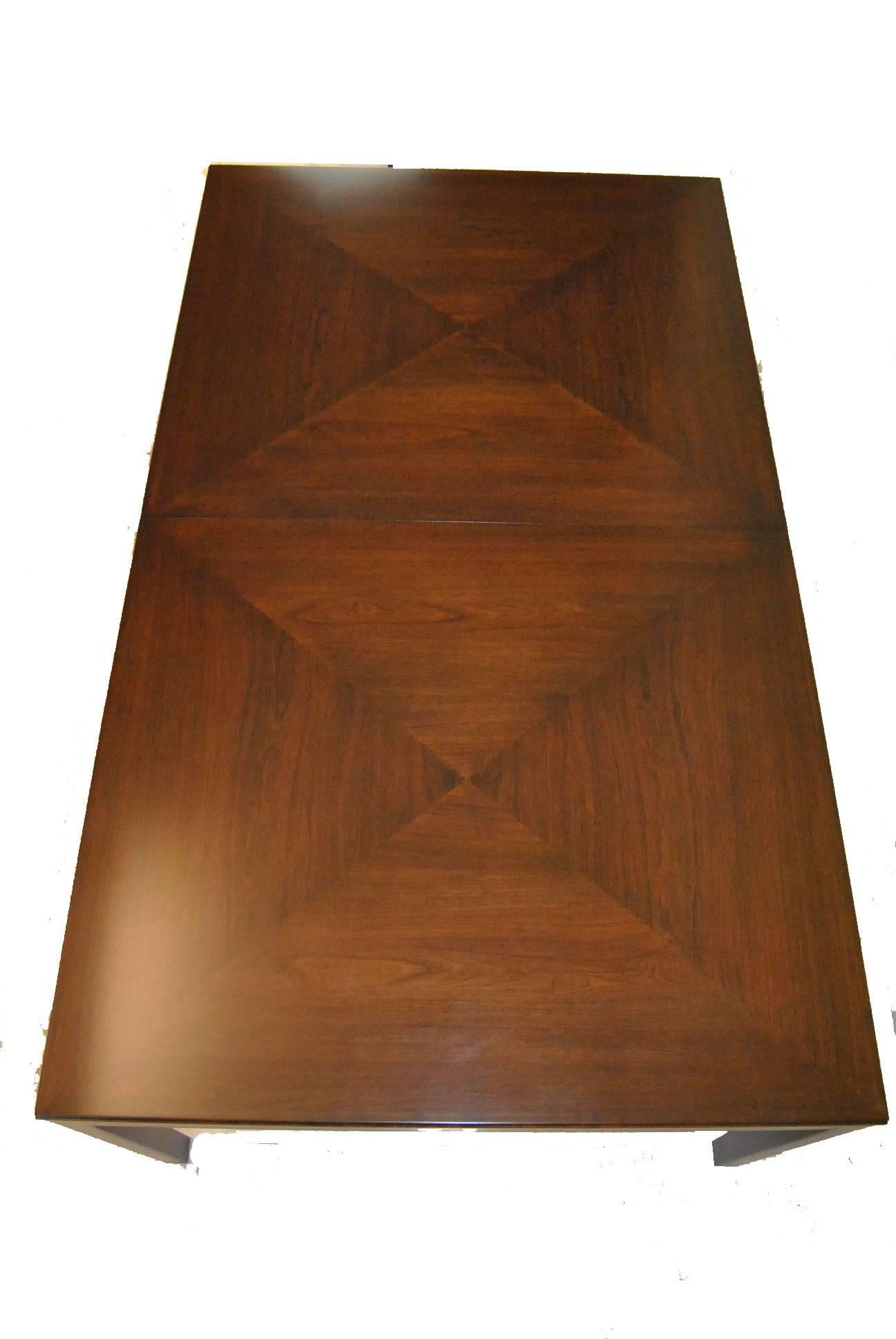 A great Mid-Century Modern dining room table by Bert England for Johnson Furniture. It has drop-down centre legs for stability when the leaves are in place, which then fold under the table to conceal when not in use. The original label is on the