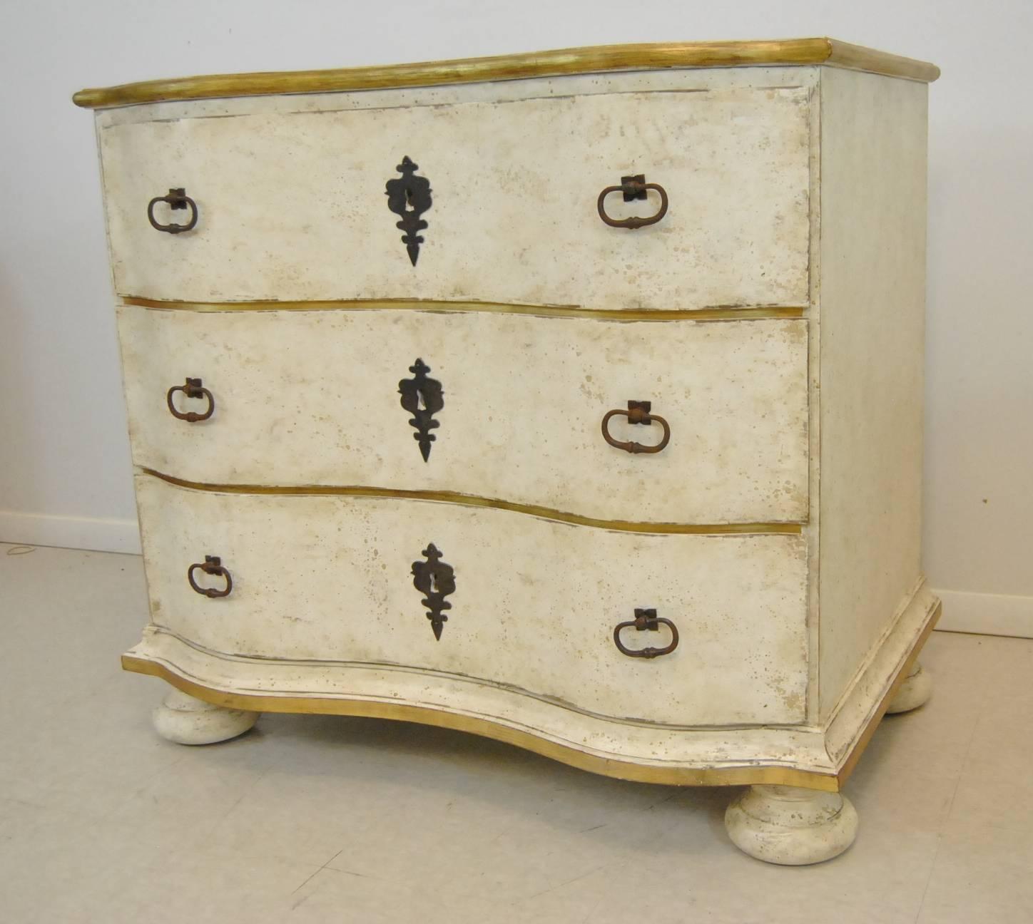 A stunning pair of French style serpentine commodes by Amy Howard. handcrafted and hand-painted in an antique white with gold trim and a wood top. These three drawer chests offer light elegant style and ample storage.