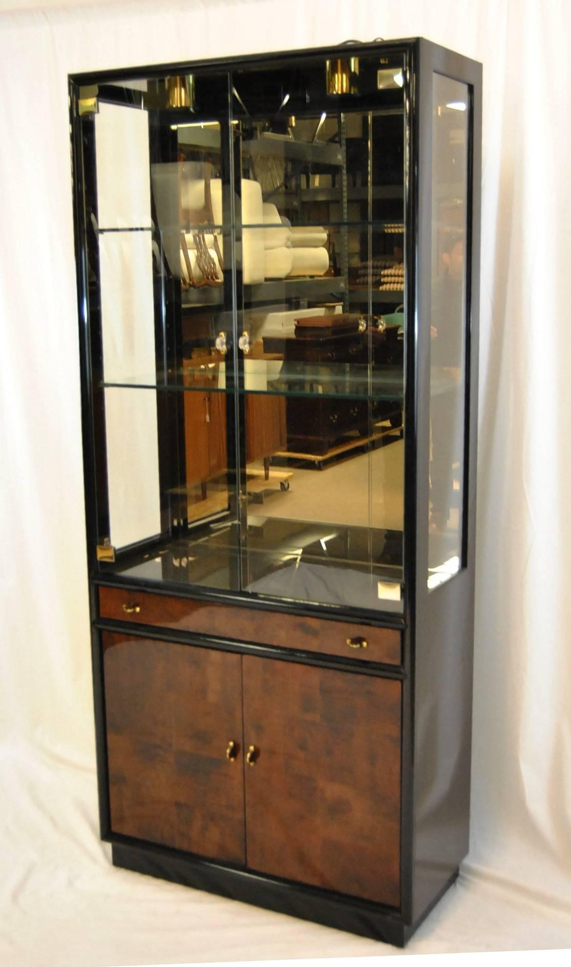 A beautiful display cabinet by Henredon as part of their Scene Three. The cabinet is black lacquer with myrtle burl drawer and door fronts. The glass display top has double doors which open to a mirrored back with two adjustable glass shelves. The