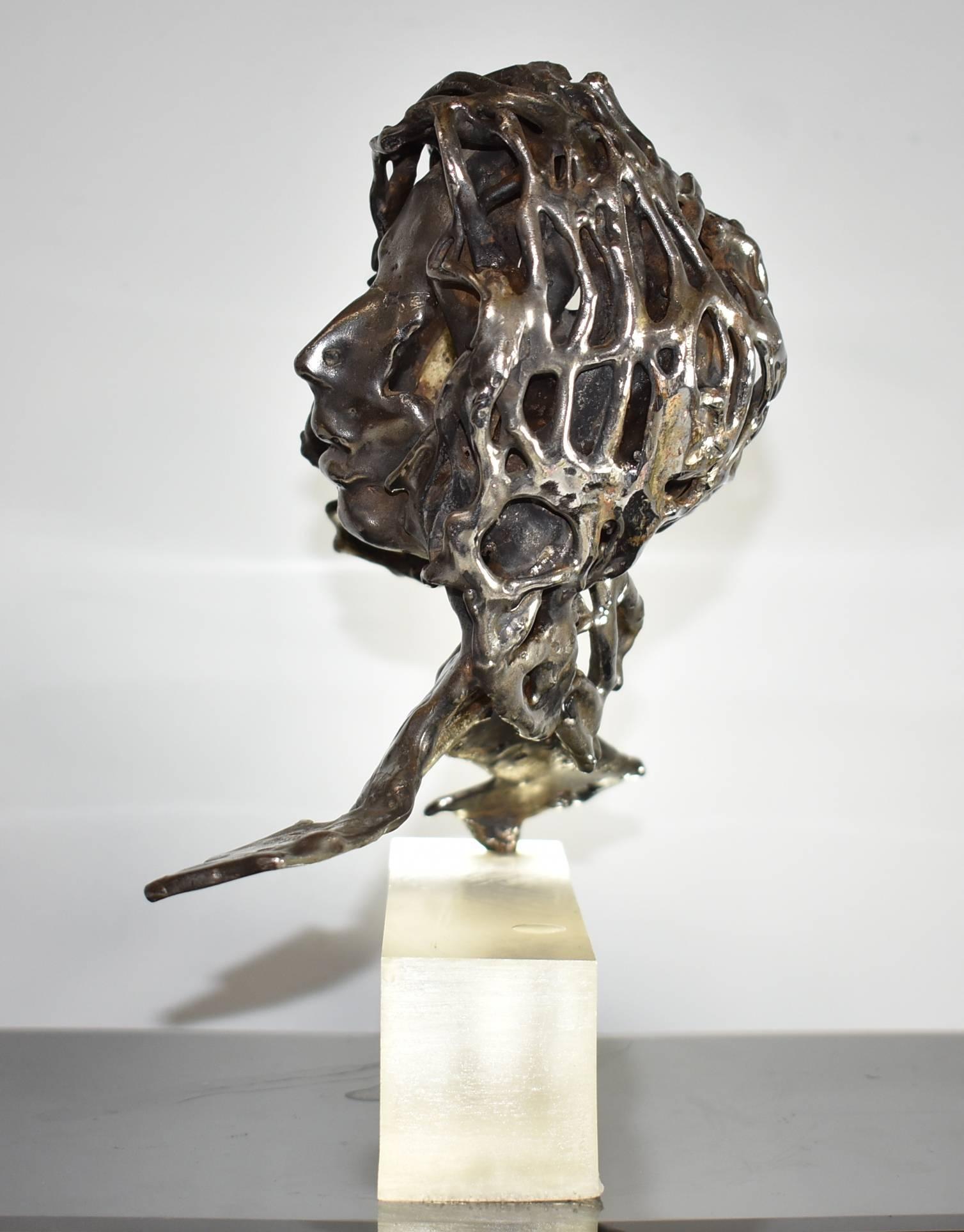 An unusual Brutalist abstract sculpture in what is believed to be nickel-plated bronze of a female bust. Sculpture is 11" tall and 11" wide and is attached to a Lucite base which is 8.5" wide by 2.5" tall. The figure is signed D.