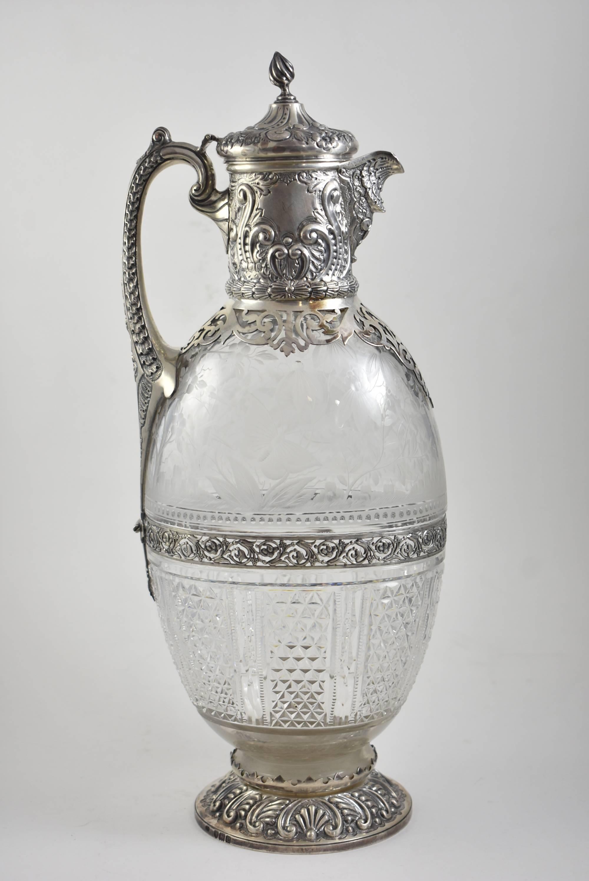 A beautiful sterling silver and etched glass pitcher by George Elder. Hallmarked G.E. It features intricate etched-glass work with crane, butterfly and flowers. Also, highly elaborate English sterling silver. The dimensions are 13.5