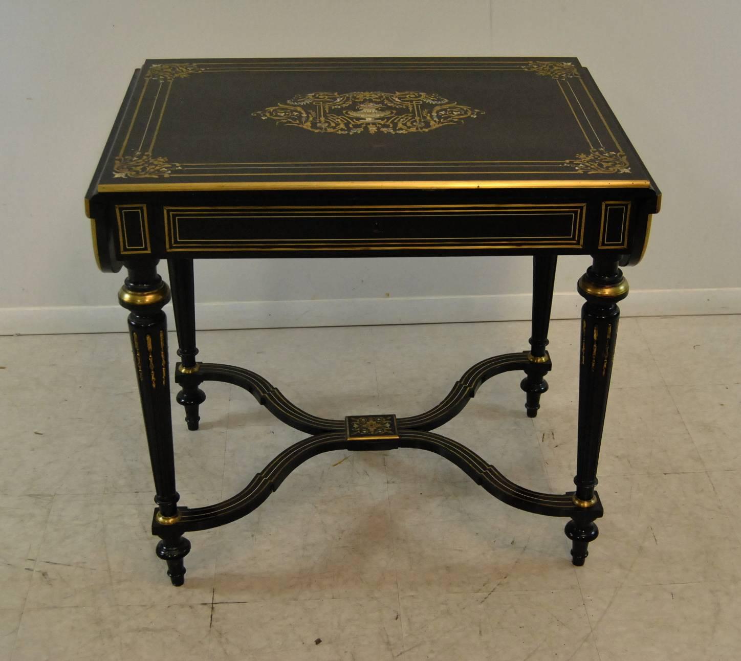 This 19th century drop leaf table features ebonized finish with inlaid flower basket design in brass and mother-of-pearl. Measure: Shaped leafs increase width to 44.5