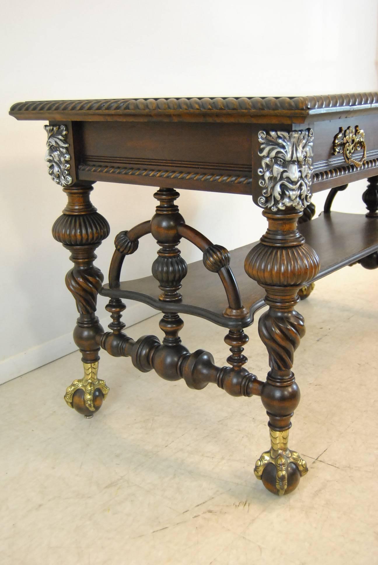 A stunning mahogany library table, circa 1890. This gorgeous table features a rope twist top border, nickel-plated cast heads of a mythical male figure and brass claw feet. The dimensions are 50