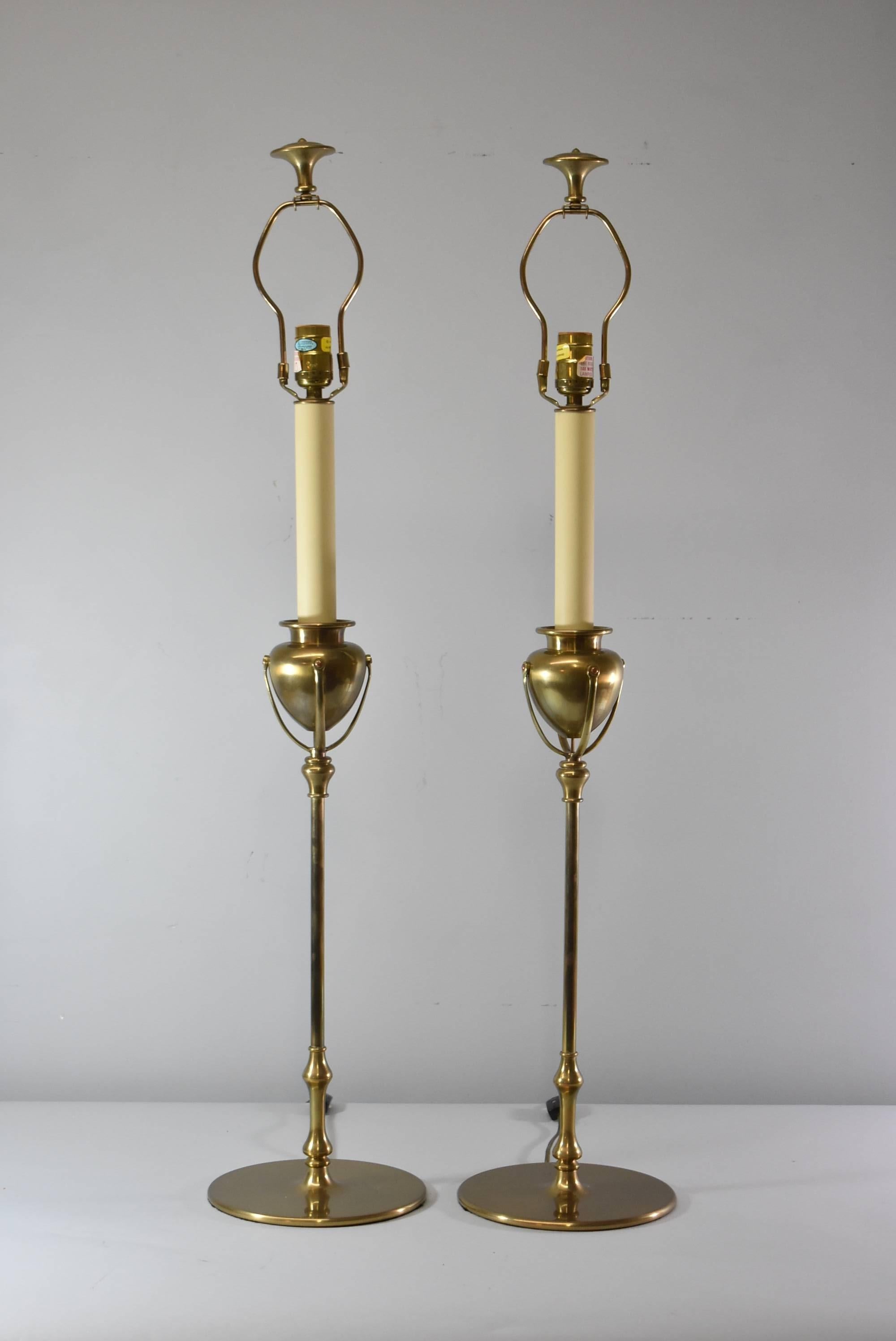 A lovely pair of brass buffet lamps by Chapman, 1985. These beautiful lamps feature a slender round brass candlestick body with an urn form in the center. Very good condition with very minimal wear. The dimensions are 37.5