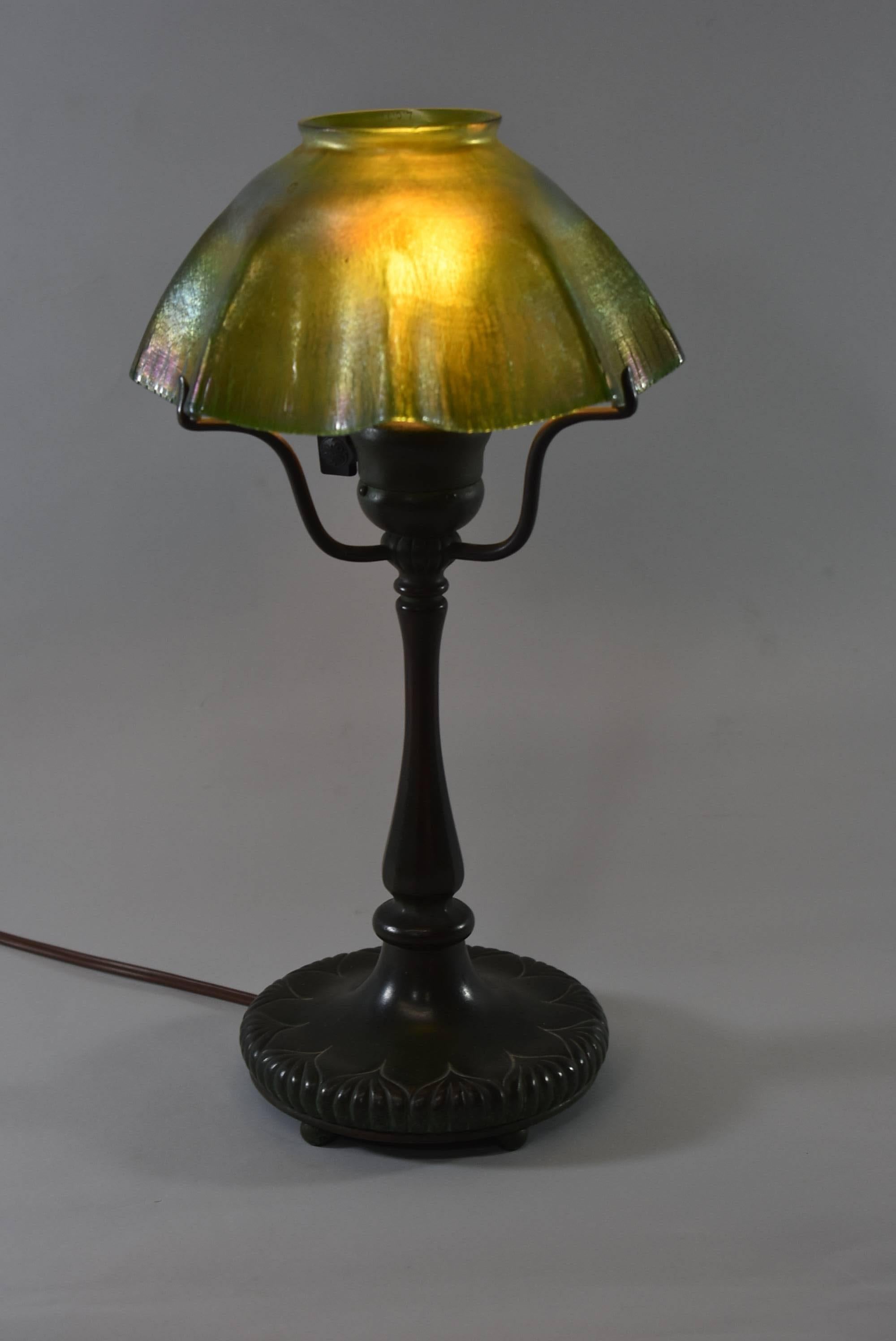 A stunning Tiffany glass table lamp. The bronze base has it's original dark green patina, is signed Tiffany Studio, New York #322. It has a three-arm spider support that holds the shade and an original G.E. socket. There is a beautiful green