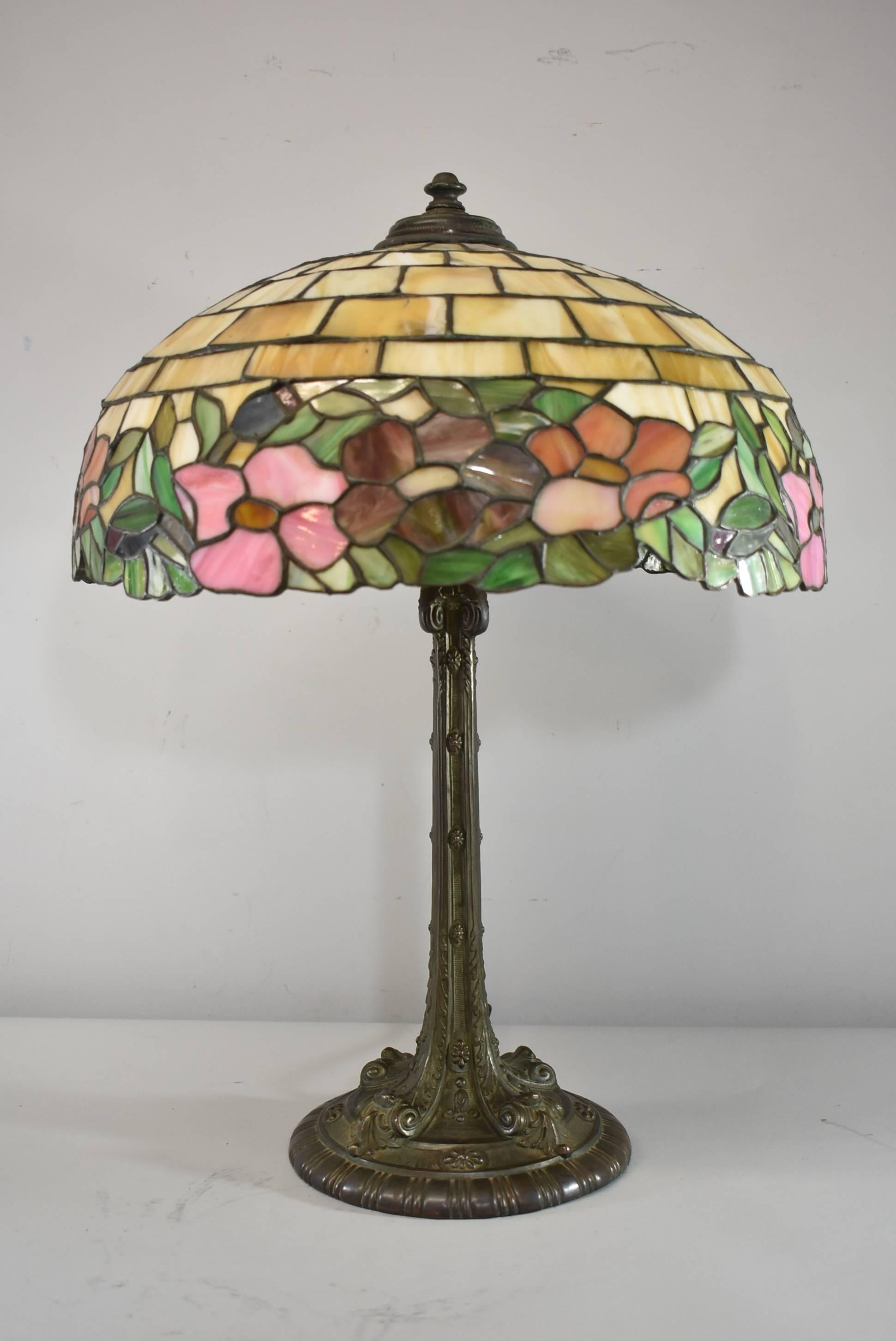 A stunning leaded slag glass table lamp by Wilkinson. This beautiful lamp features blooming and budding peonies flowers. Good wiring with a new cloth cord. The base has a great patina. The dimensions are 25