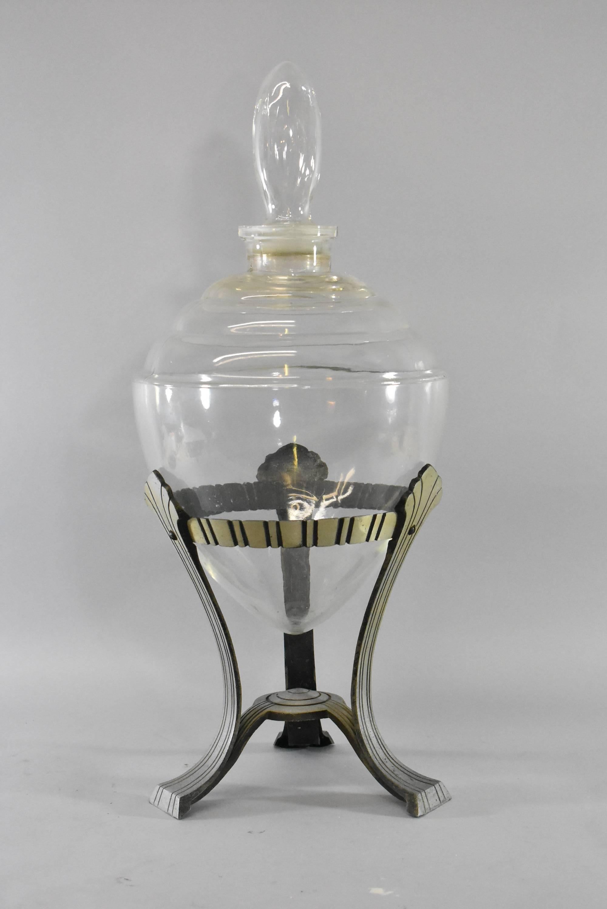 A fantastic Art Deco style apothecary display jar. It features a removable stopper with a three legs aluminum silver tone stand. The dimensions are 23.5
