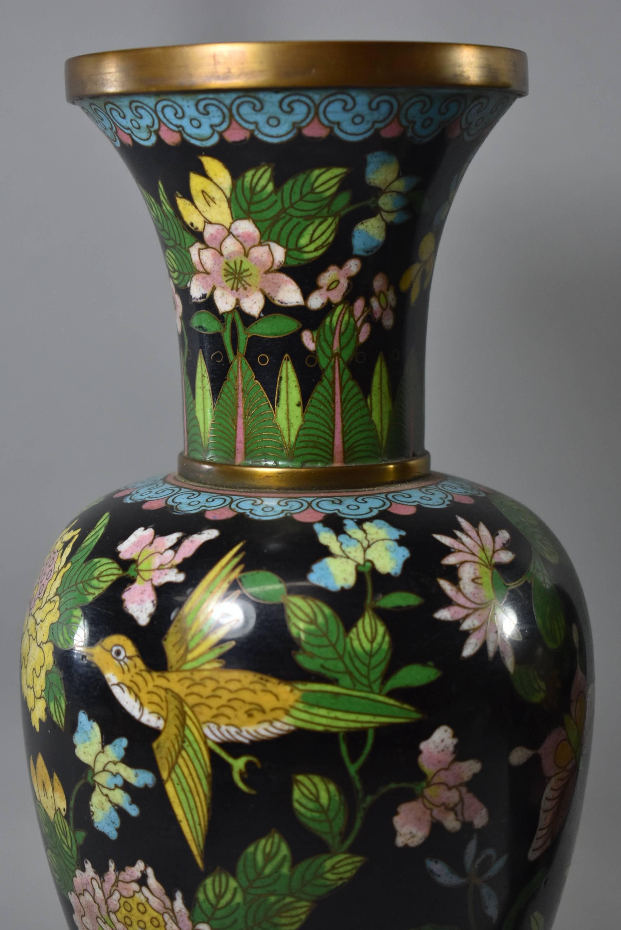 A beautiful pair of turn of the century Chinese cloisonne vases. These stunning vases features a black background with vibrant flowers, birds, butterflies and folilage. The brass body is 12.5
