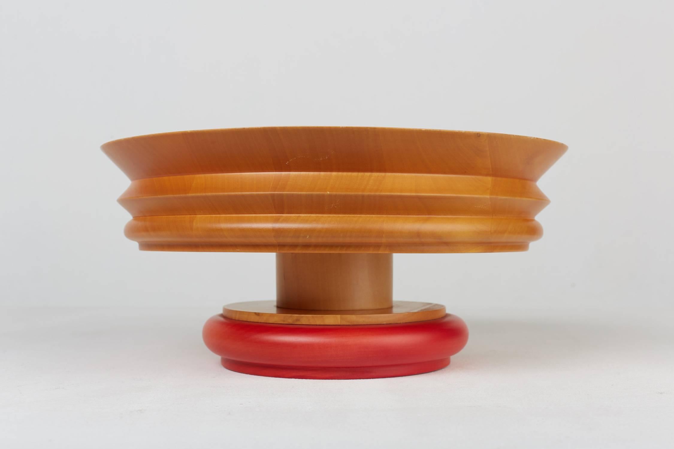 Wooden bowl.
Design by Ettore Sottsass (1994).
Manufactured by Alessi, Italy.
Measures: D 30 cm, H 14 cm.
Turned limewood, foot varnished in red.
Out of production.