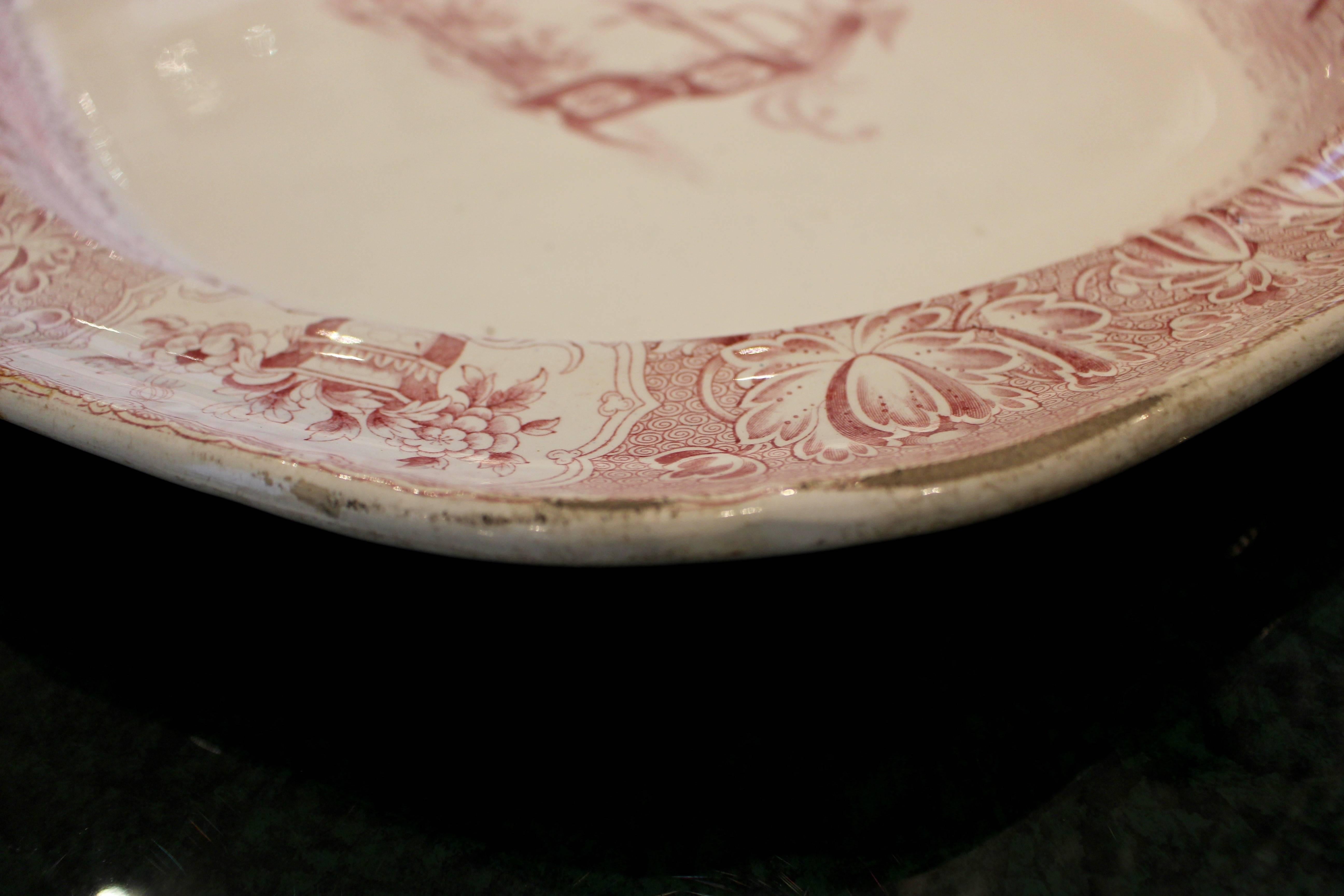 A 19th century English octogonal faience serving platter with scalloped rim decorated in red with a chinoiserie scene. The central scene depicts a table ornamented with pierced Chinese lattice work supporting a sizable vase with flowers alongside