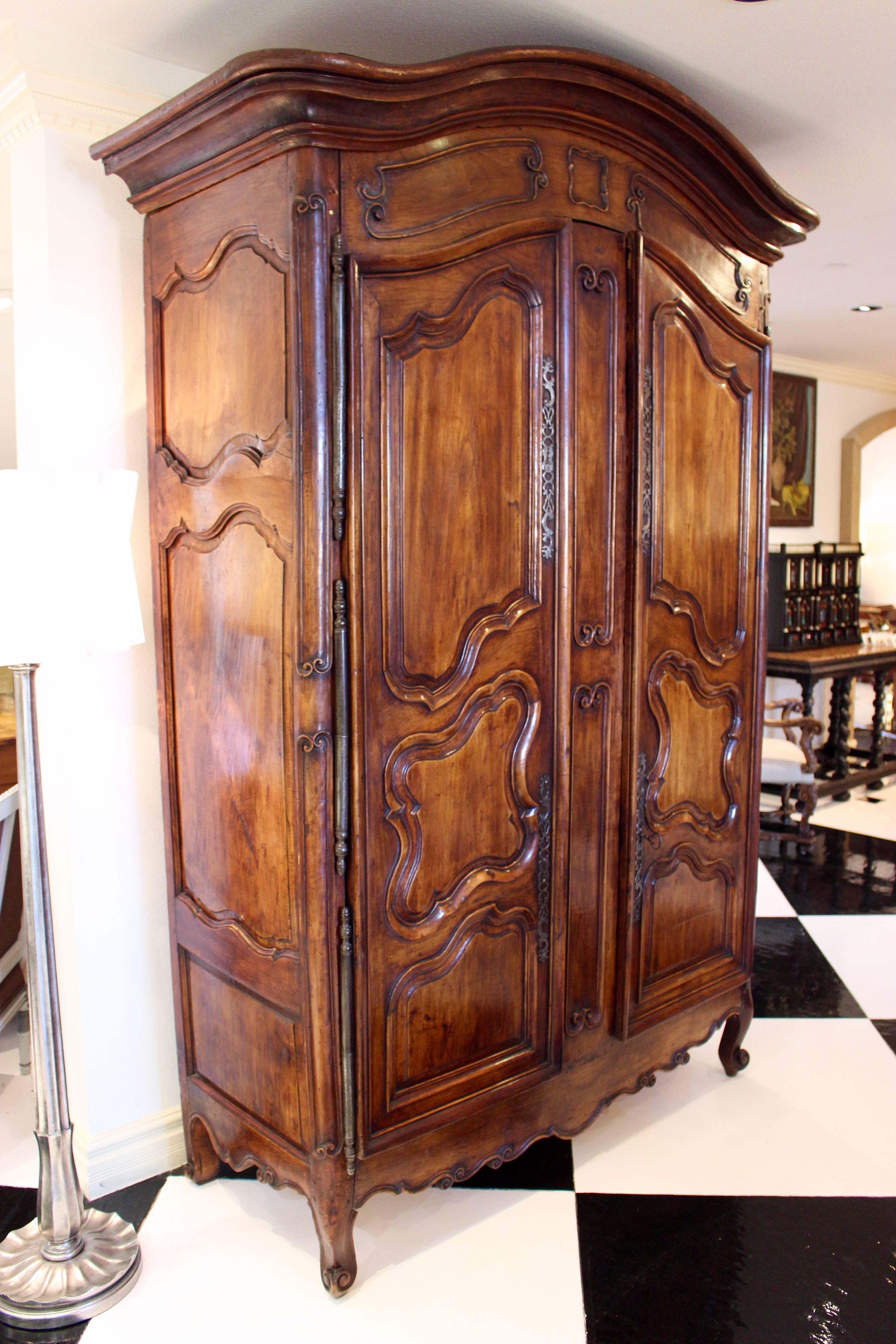 Armoire française en bois fruitier d'époque Louis XV, datant de la première moitié du XVIIIe siècle, avec un plateau à bonnet, des portes à panneaux surélevés, une jupe festonnée et des pieds à volutes. Née au milieu du règne de Louis XV, cette