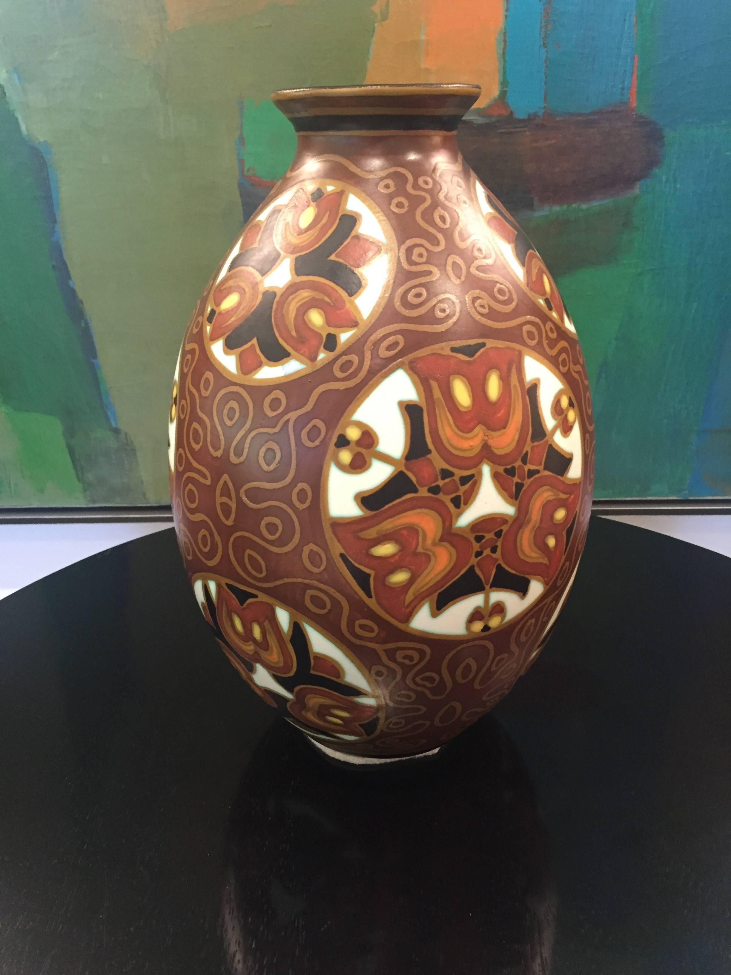 An Art Deco ovoidal vase in polychrome matte enameled earthenware with a black everted neck from the Belgian Boch Frères Keramis Factory. The floral motif in warm shades covering the body features stylized tulips in white roundels. The brown