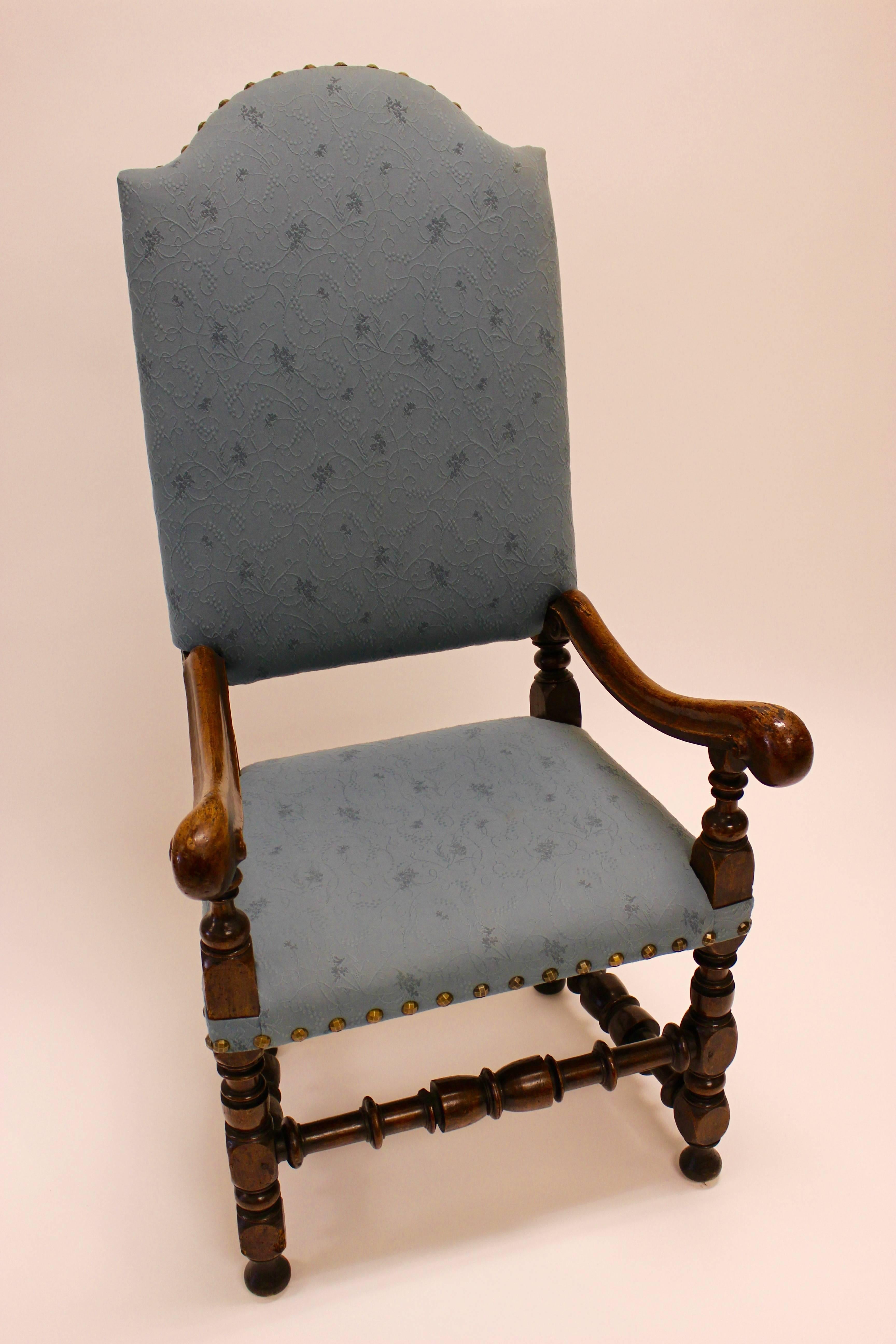 Italian Baroque walnut armchair, the arched upholstered back with tack trim and finials above volute scrolled arms on baluster supports and upholstered seat raised on baluster and block turned legs, joined by turned stretchers. Late 17th/early 18th