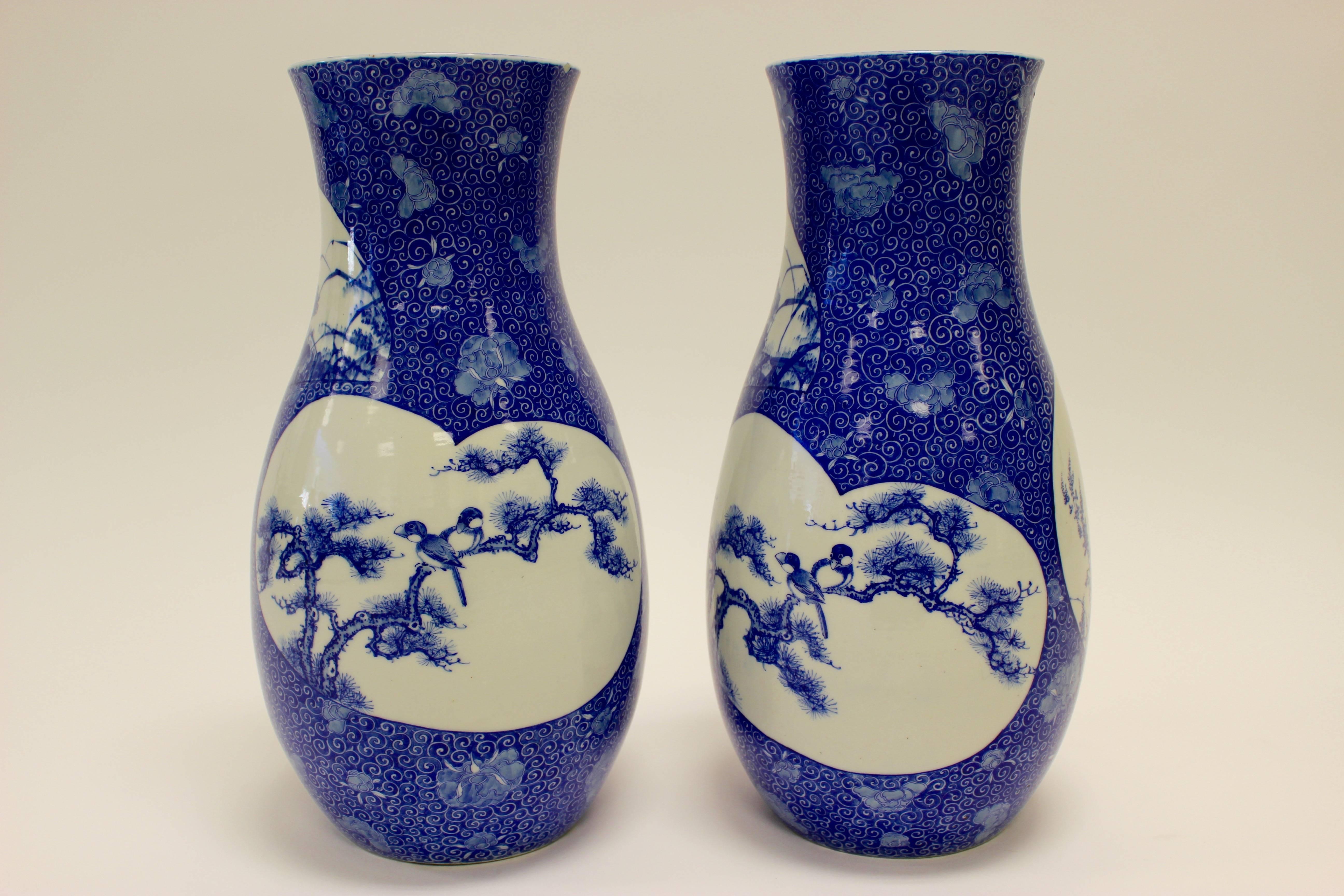 A pair of Japanese underglaze blue and white porcelain baluster vases from the late 19th century painted with shaped panels of flowers, insects and birds. Formerly in the Kentshire collection, each piece features a round panel with a fly on a prunus