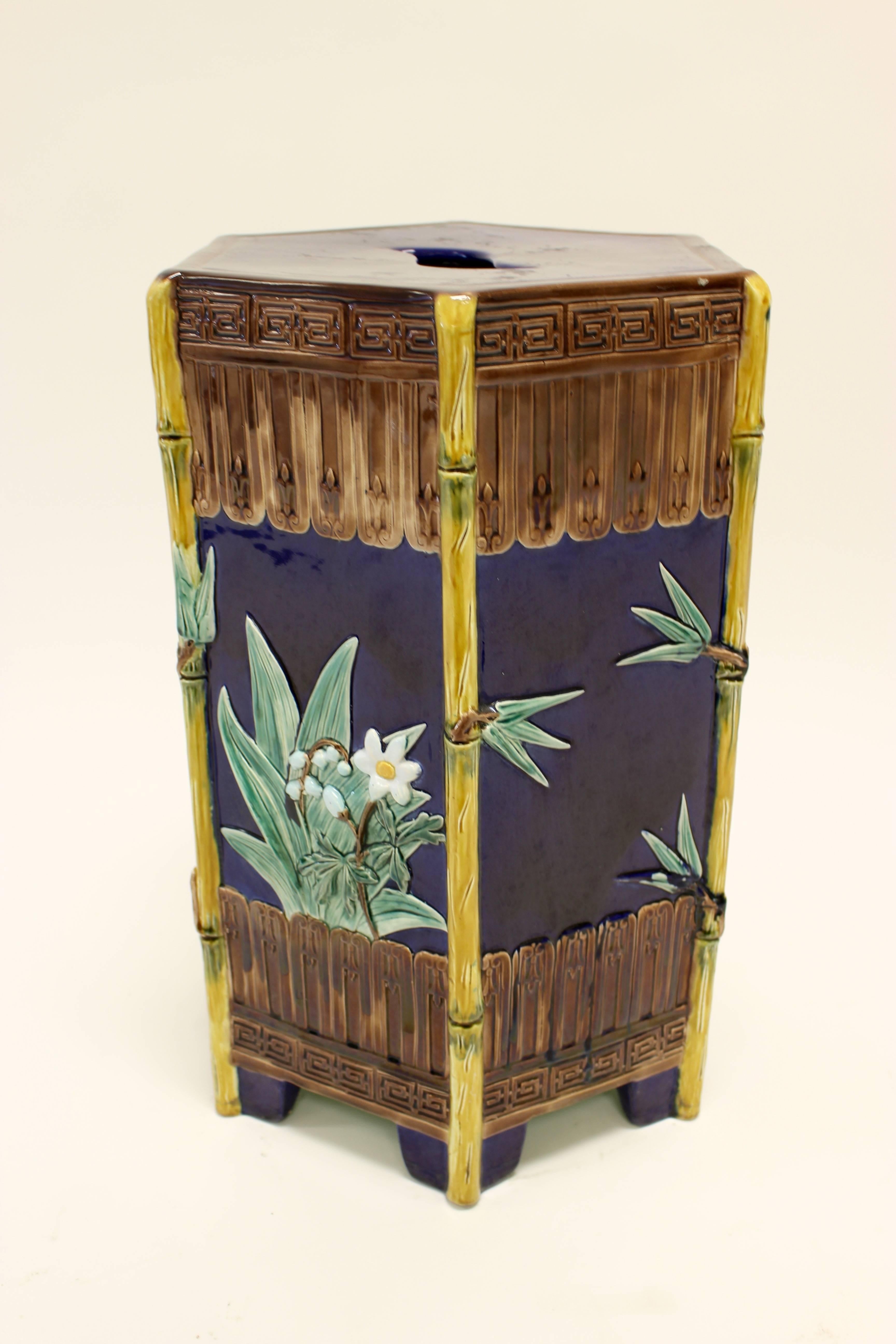 A porcelain garden seat of hexagonal form decorated in relief with lily of the valley flowers and bamboo leaves on a cobalt-blue ground. Molded bamboo-shaped mounts ending in bracket feet adorn the corners of the piece, nicely enhancing its