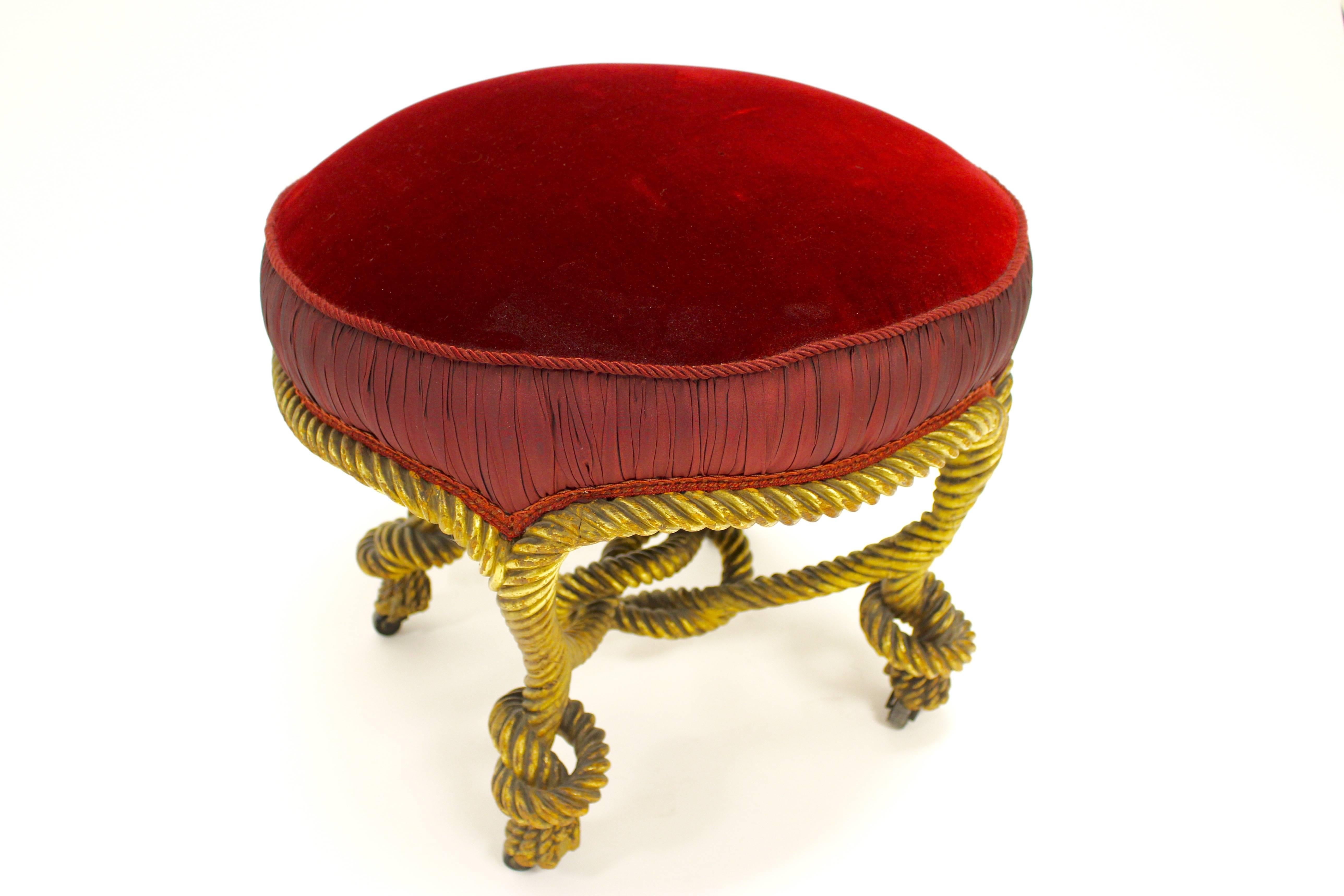 Eleganter Hocker aus vergoldetem Holz im Stil von Napoleon III. mit einem runden, gepolsterten Sitz, der mit rotem Samtstoff bezogen ist. Die äußere Kante des Sitzes ist mit wunderschönen Raffungen versehen, die von seilartigen und geschwungenen
