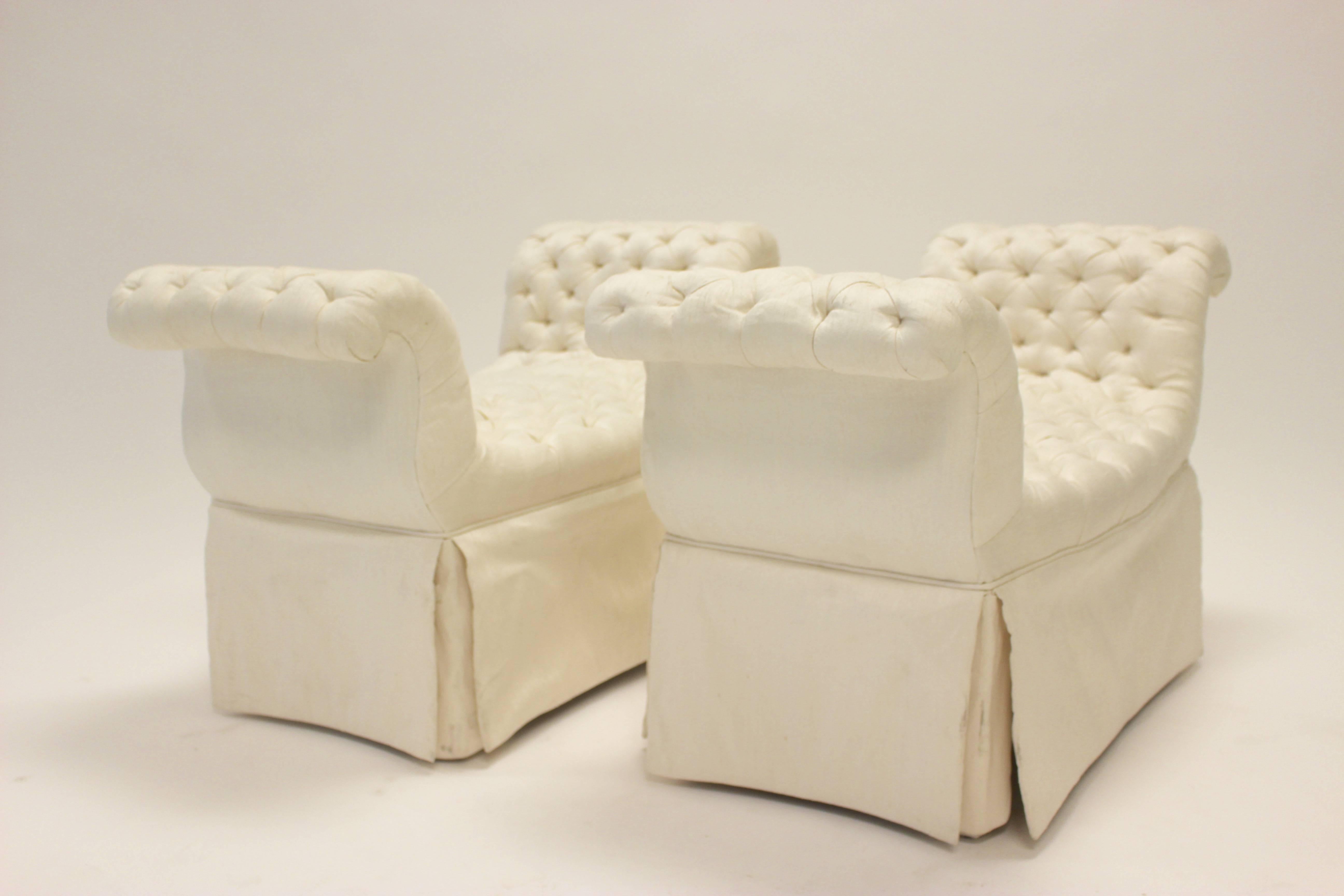 A pair of benches upholstered in cream-colored button-tufted silk from the 20th century. Each bench features a deep diamond button-tufted seat and rolled pleated side arms above a large skirt providing storage space. Possibly by the famous 20th