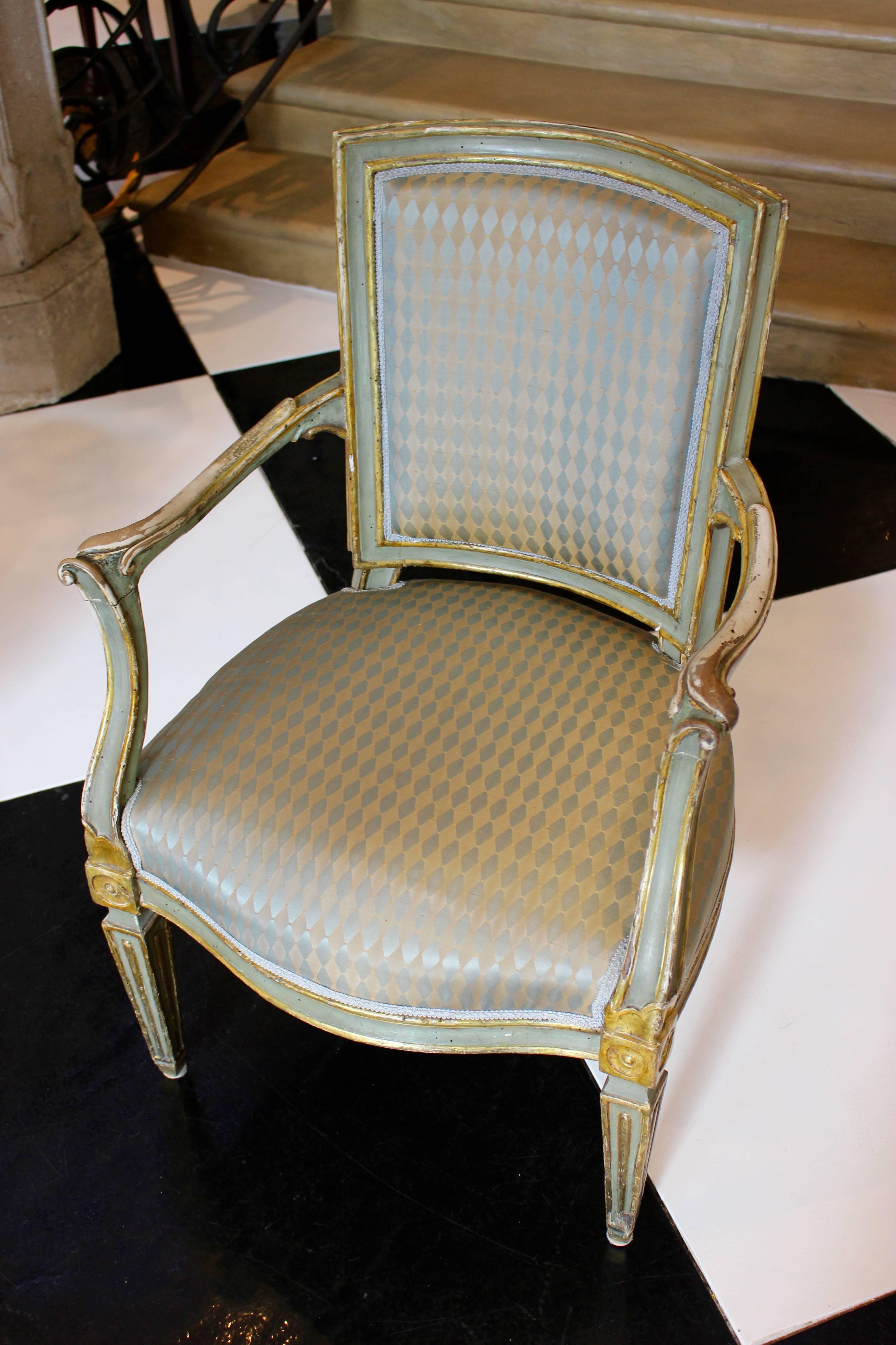 A pair of Italian neoclassical period painted and parcel-gilt armchairs from the late 18th century, with padded backs, out-curved arms, gilt medallions, fluted tapering legs and upholstery. Born at the end of the 18th century at a time when the