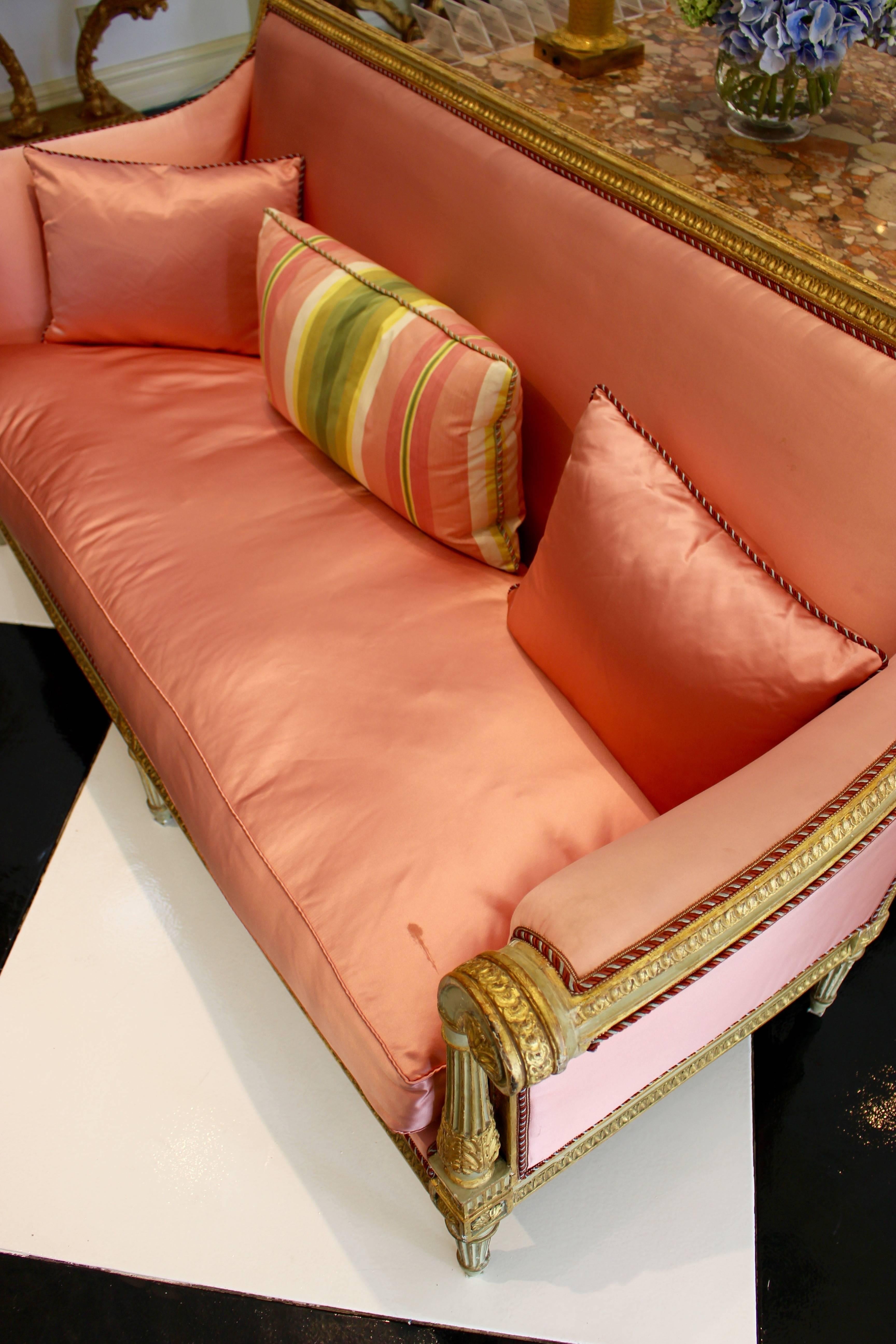 Canapé d'époque Louis XVI peint et doré à la feuille, datant de la fin du XVIIIe siècle, avec un dossier rectangulaire, des bras à enroulements, des pieds cannelés et un profond rembourrage de couleur cantaloup. Ce canapé français présente une