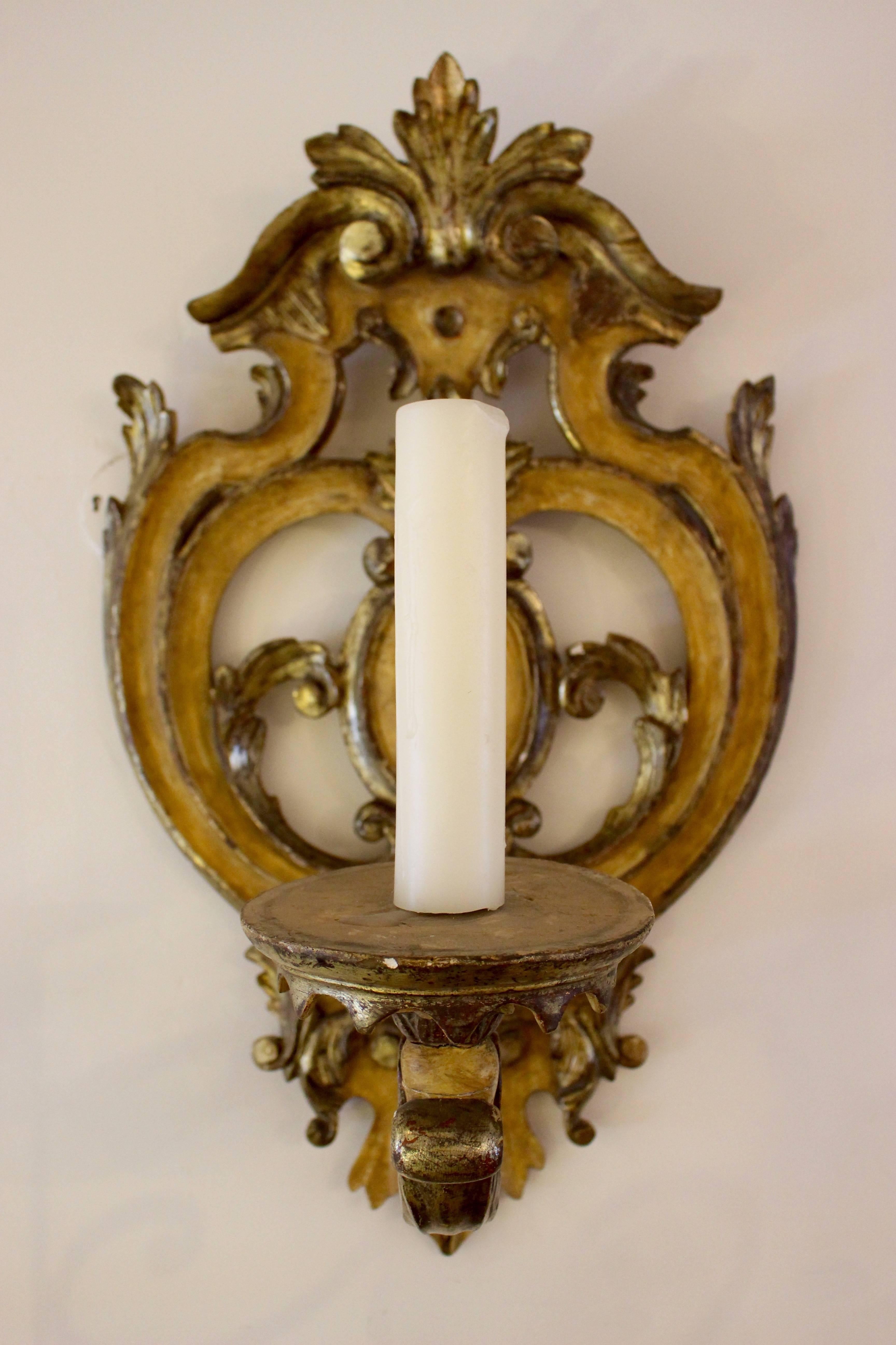 Italienischer Barock-Wandleuchter aus geschnitztem, paketvergoldetem und ockerfarbenem Holz aus der ersten Hälfte des 18. Die wunderschön geformte und durchbrochene Rückplatte zeigt ein zentrales Medaillon, das von kunstvollen symmetrischen