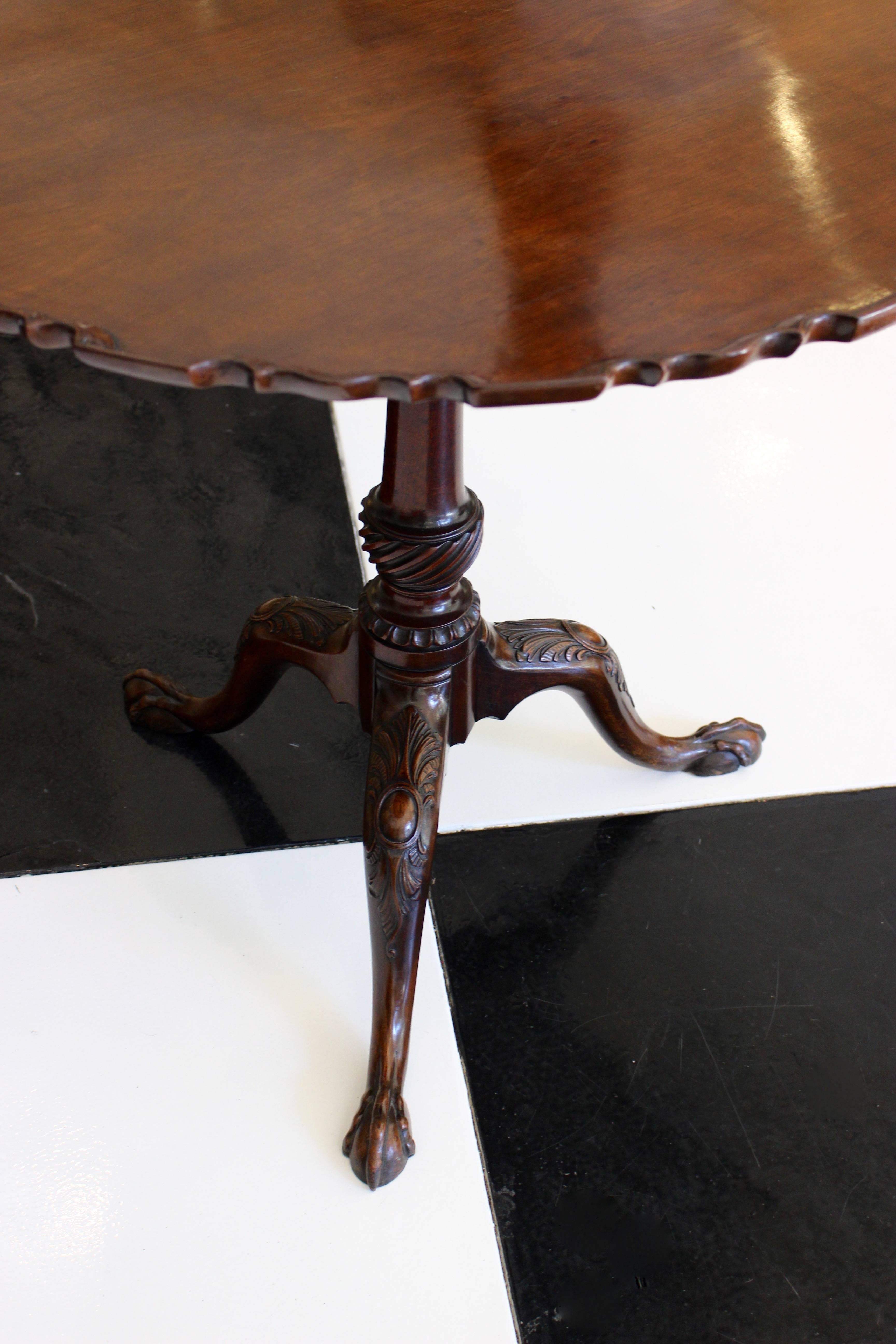 An English George II period mahogany tripod table from the mid-18th century, with pie-crust tilt-top, turned baluster stem and carved cabriole legs. Born during the third quarter of the 18th century, this English mahogany table features a circular