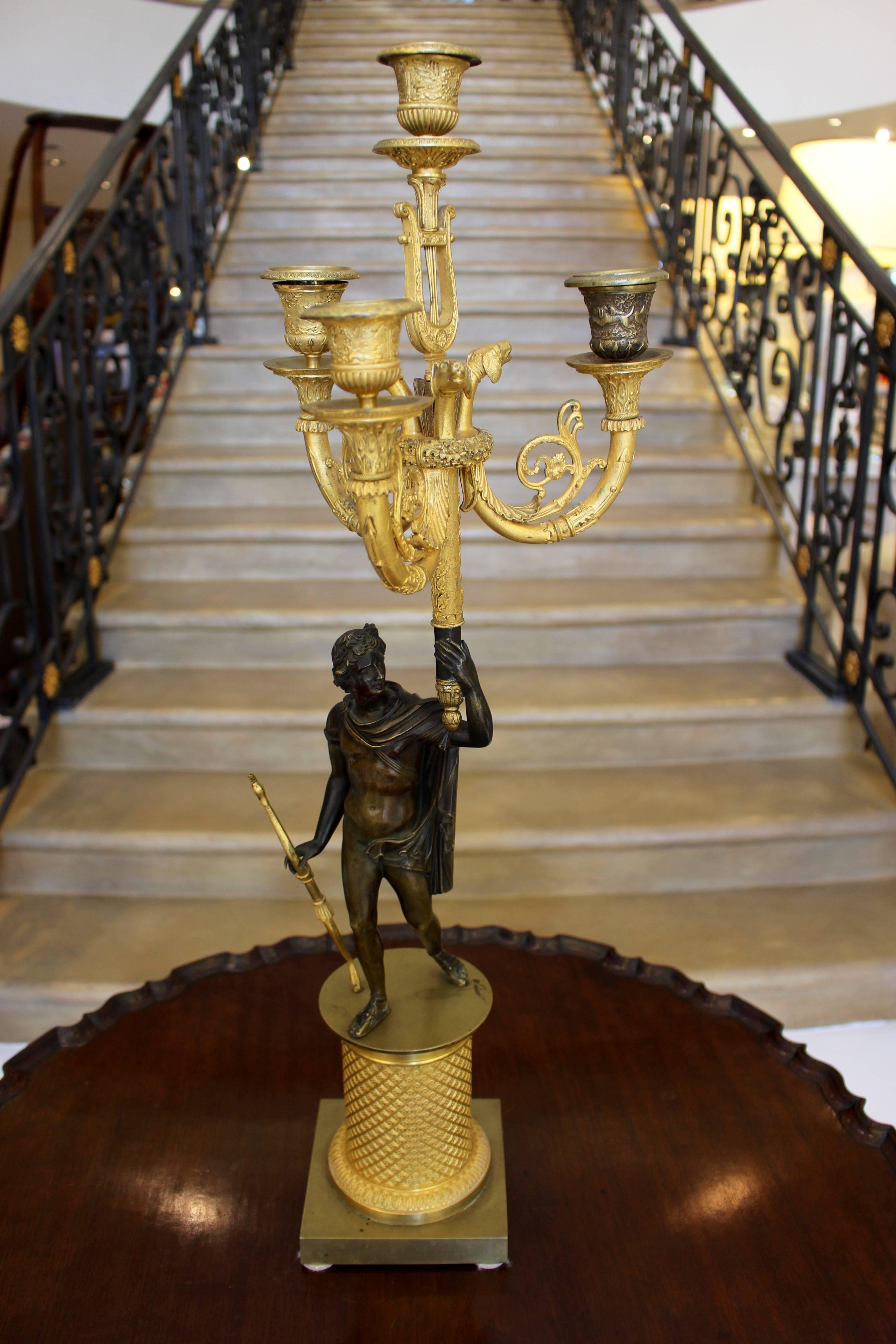 A pair of French Charles X period ormolu and painted bronze four-light candelabra from the early 19th century with sculptures of the Olympian gods Apollo, god of music and Diana, goddess of hunting. Modeled after the famous antique Roman sculptures