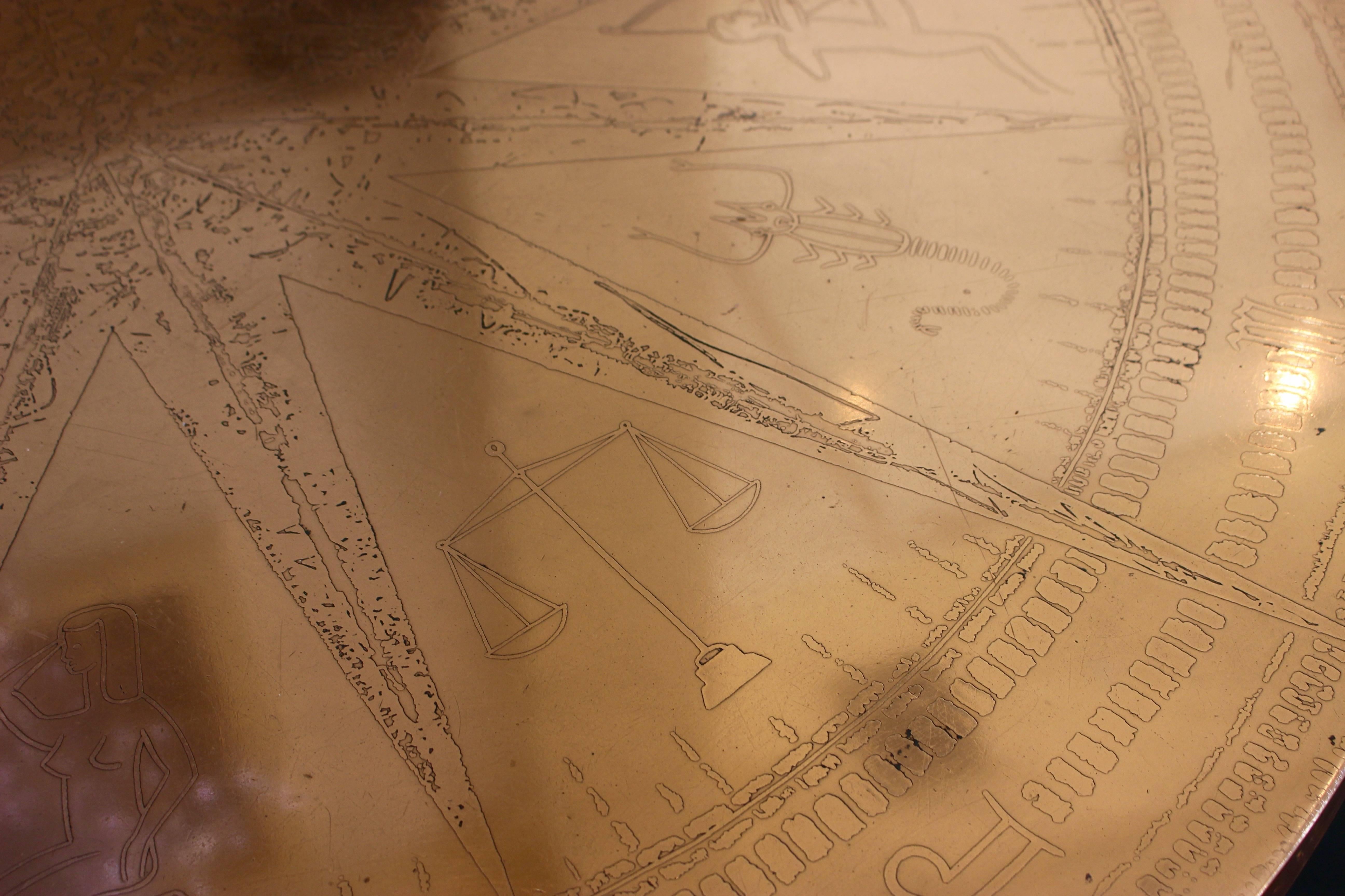 Une table basse française inhabituelle du début du 20e siècle avec des motifs astrologiques comprenant un élégant plateau circulaire en cuivre et un piédestal chromé à quatre rayons. Les douze signes du zodiaque sont représentés entre les branches