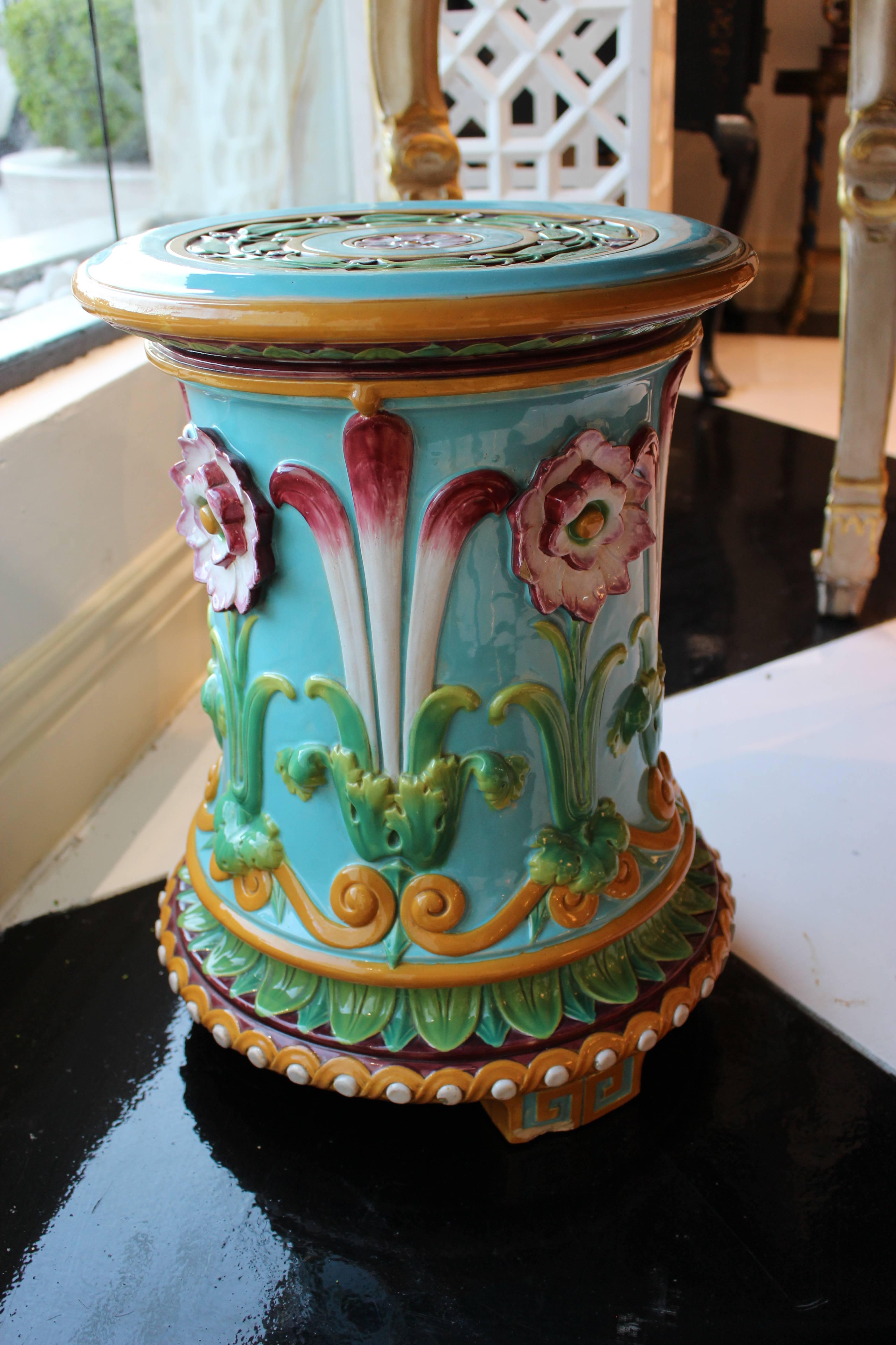 An English Minton Majolica 1876 garden seat of waisted cylindrical form moulded in high relief with cheerful colors. Pink-edged passion flowers and palmettes alternate on a cheerful turquoise ground contrasting with an orange scrolling border over
