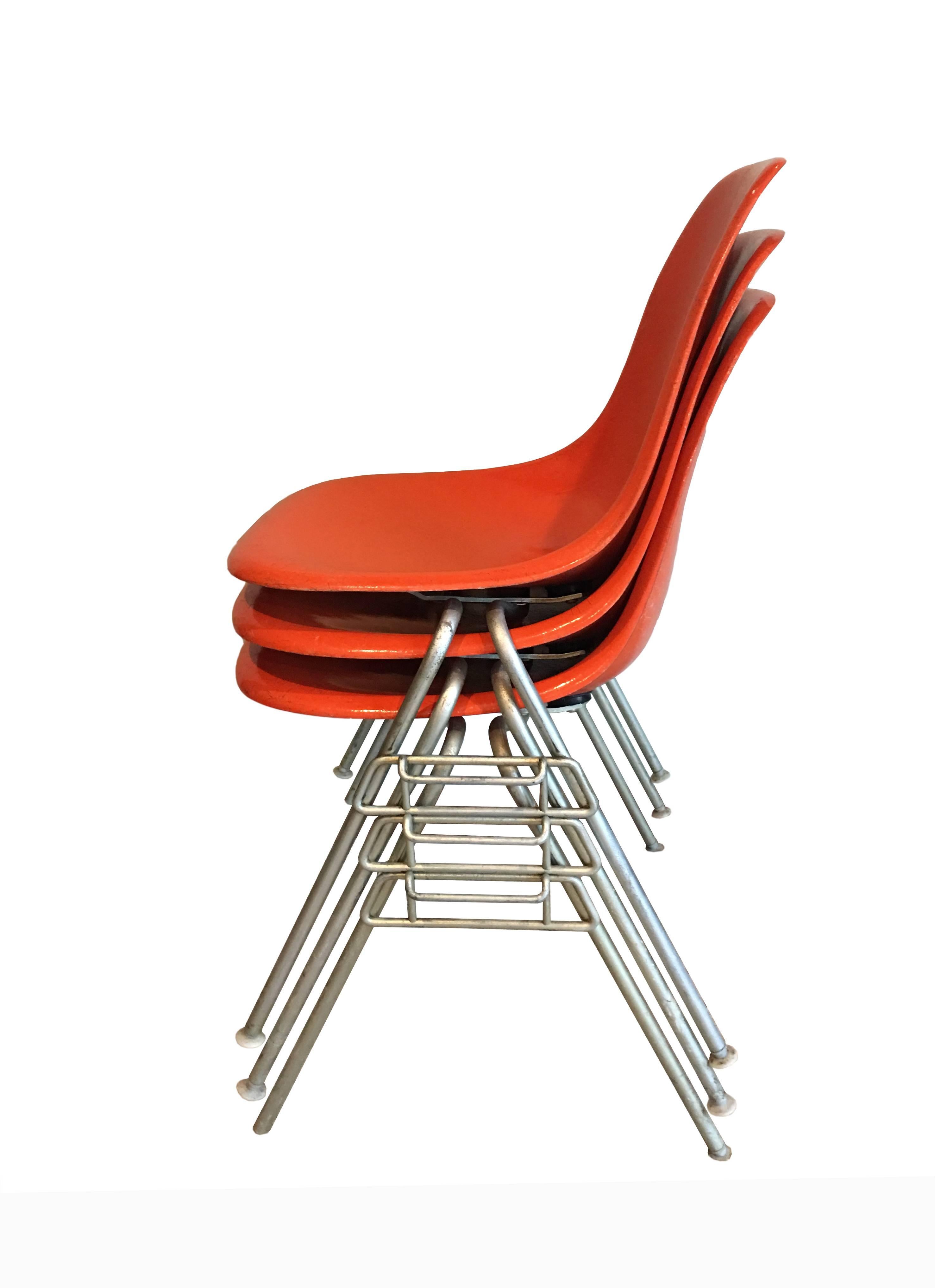 Stackable, orange Herman Miller chairs designed by Charles and Ray Eames. A timeless Classic designed to meet a multitude of seating needs. Additional photos available upon request. All chairs are embossed with the Herman Miller logo. The chairs