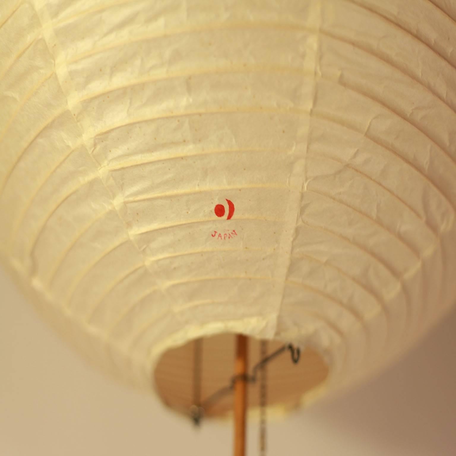 Beautiful bamboo and cast iron floor lamp designed by Isamu Noguchi. Vintage paper shade in excellent condition.
