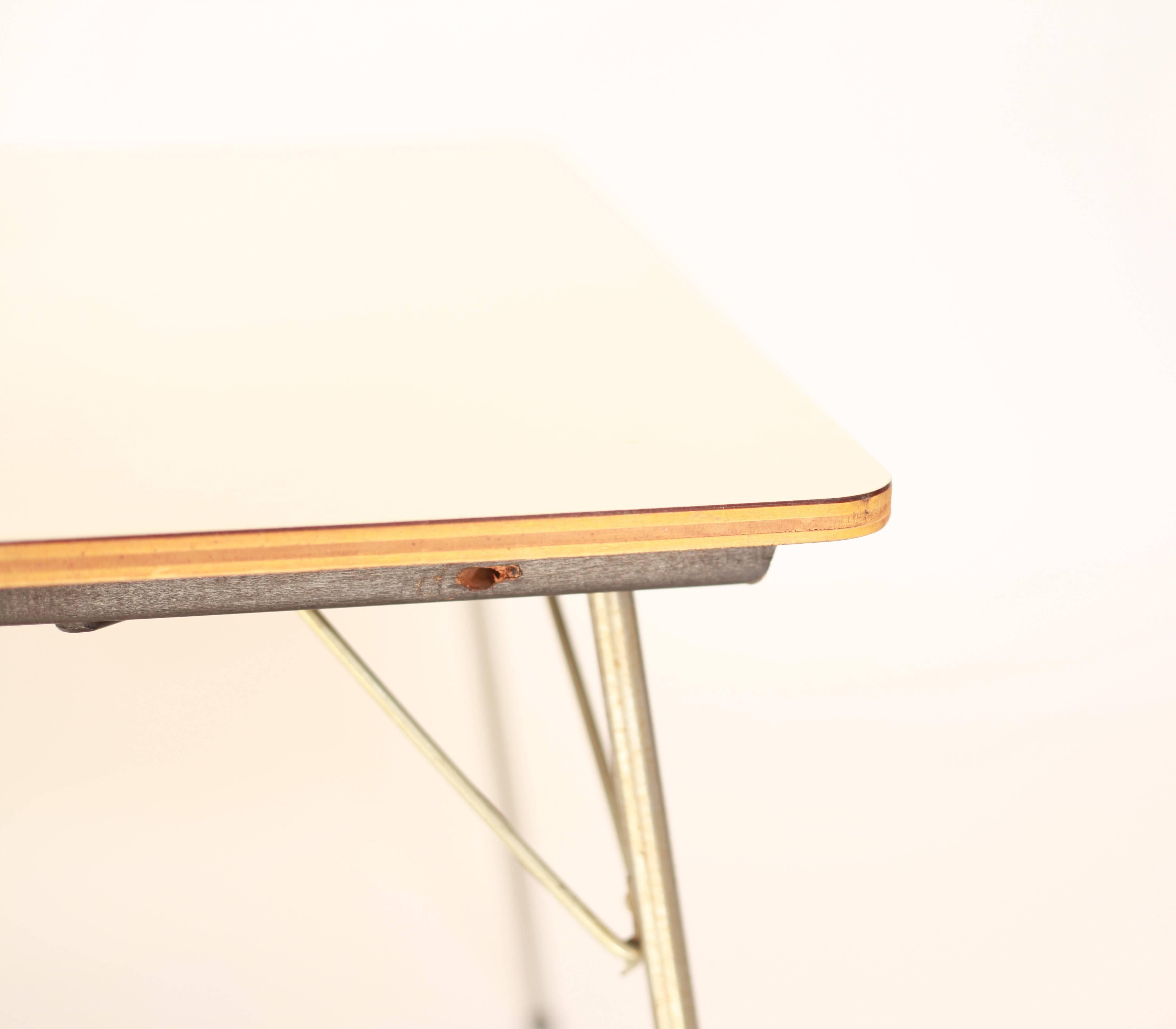 This early rare Eames IT-1 table features unique hardware which hold the leg braces on. This hardware is unseen on other production tables. Production models have holes drilled into the wood and the leg braces fit into these holes. This model