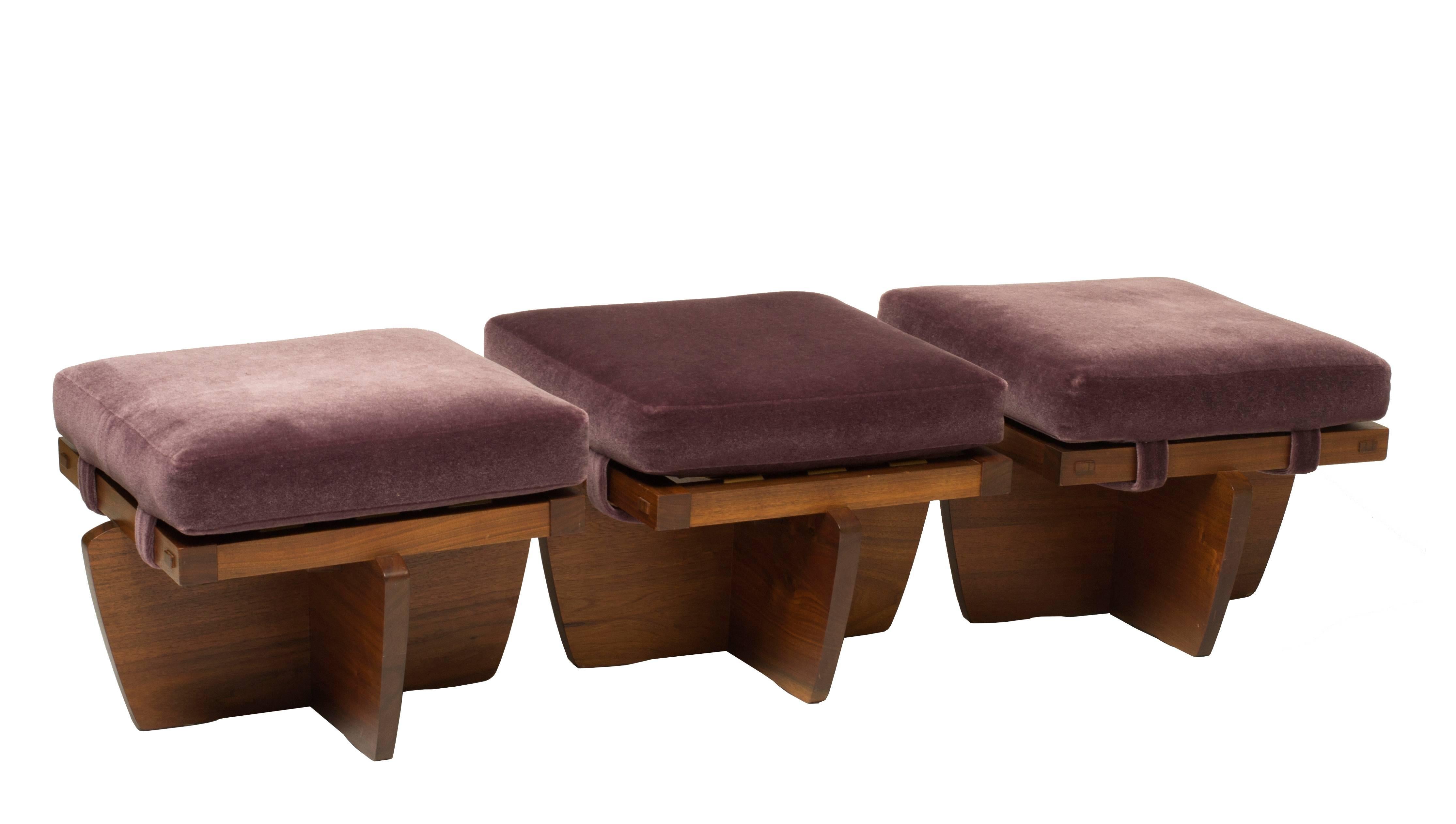 Three matching Nakashima Greenrock ottomans. Produced in 1997, these beautiful Walnut stools feature the original purple velvet upholstery. Each Ottoman is sIgned "Nakashima", numbered, dated and authenticated by the Nakashima Studio.