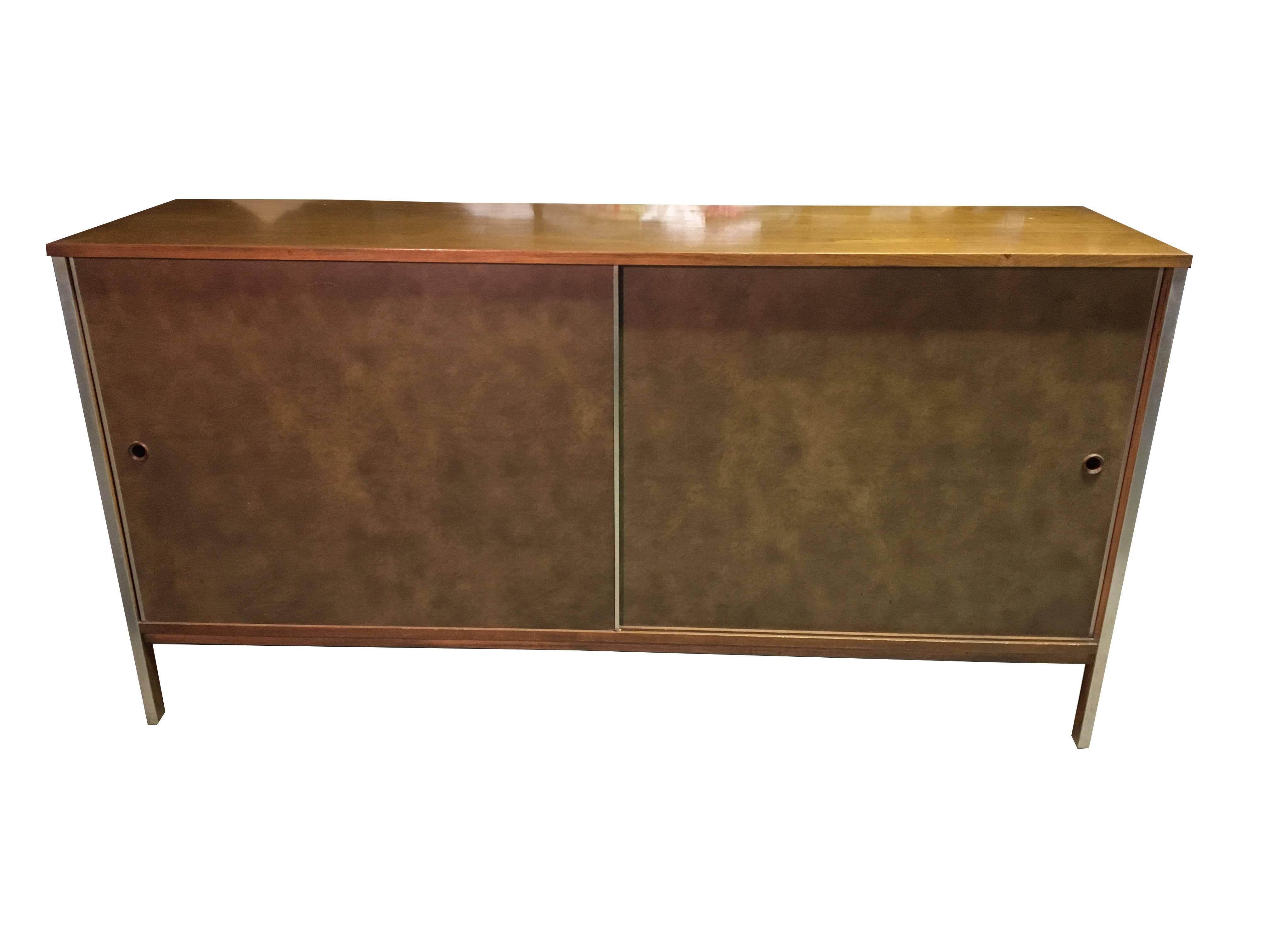 Beautiful Paul McCobb credenza comprised of clean lines and simple yet smart design. Walnut and aluminum with vinyl covered sliding doors. Designed for the Calvin.