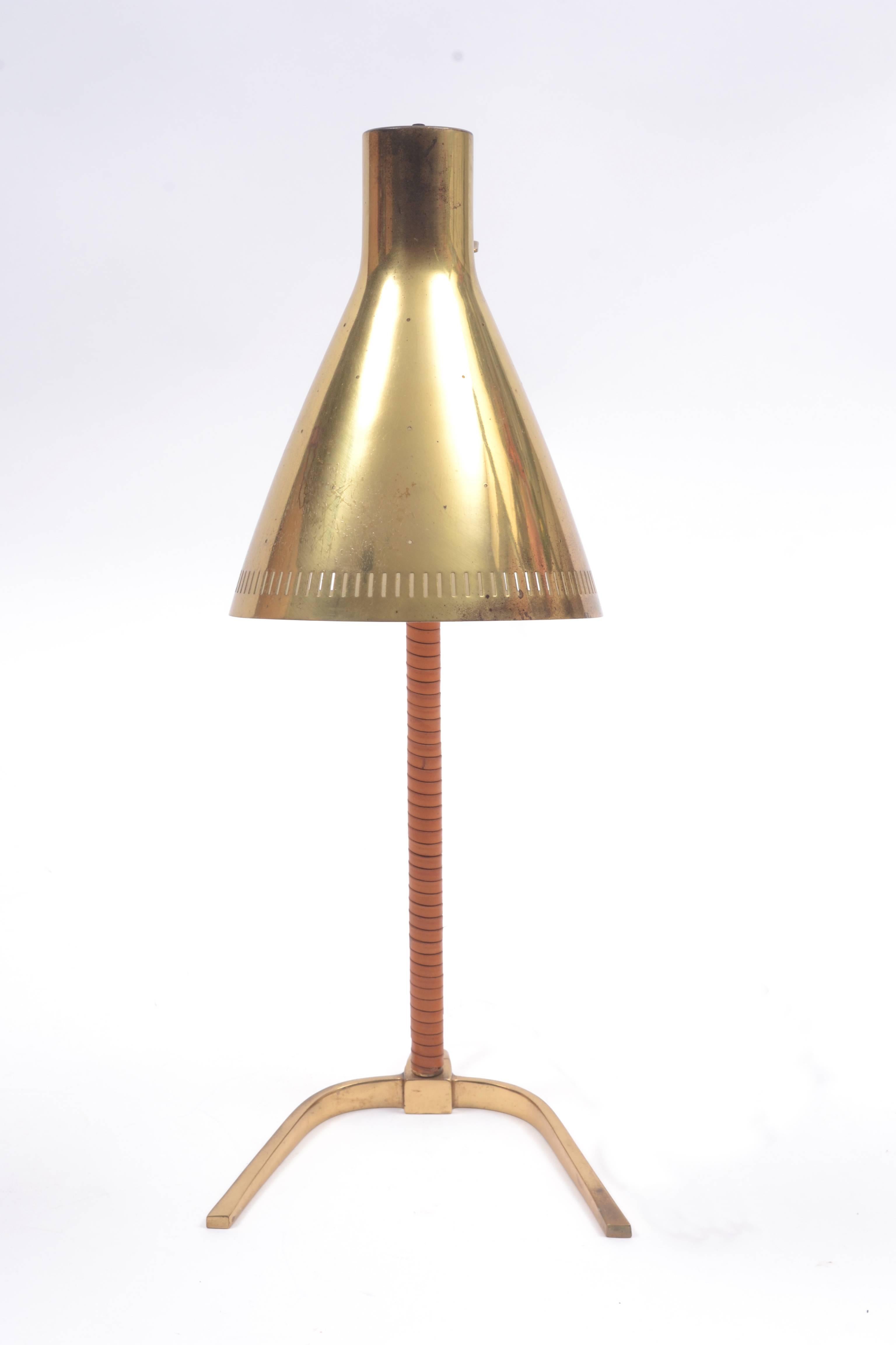 Early Paavo Tynell 9224 lamp featuring articulating, perforated brass shade with brass base and stem wrapped in leather. Bottom stamped 